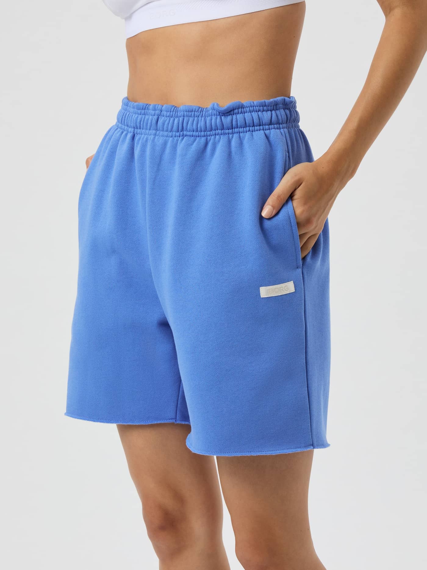 Front view of a woman wearing the Studio Oversized Sweatshorts in Ultramarine (Blue) with a relaxed fit and white satin logo. - Image 2