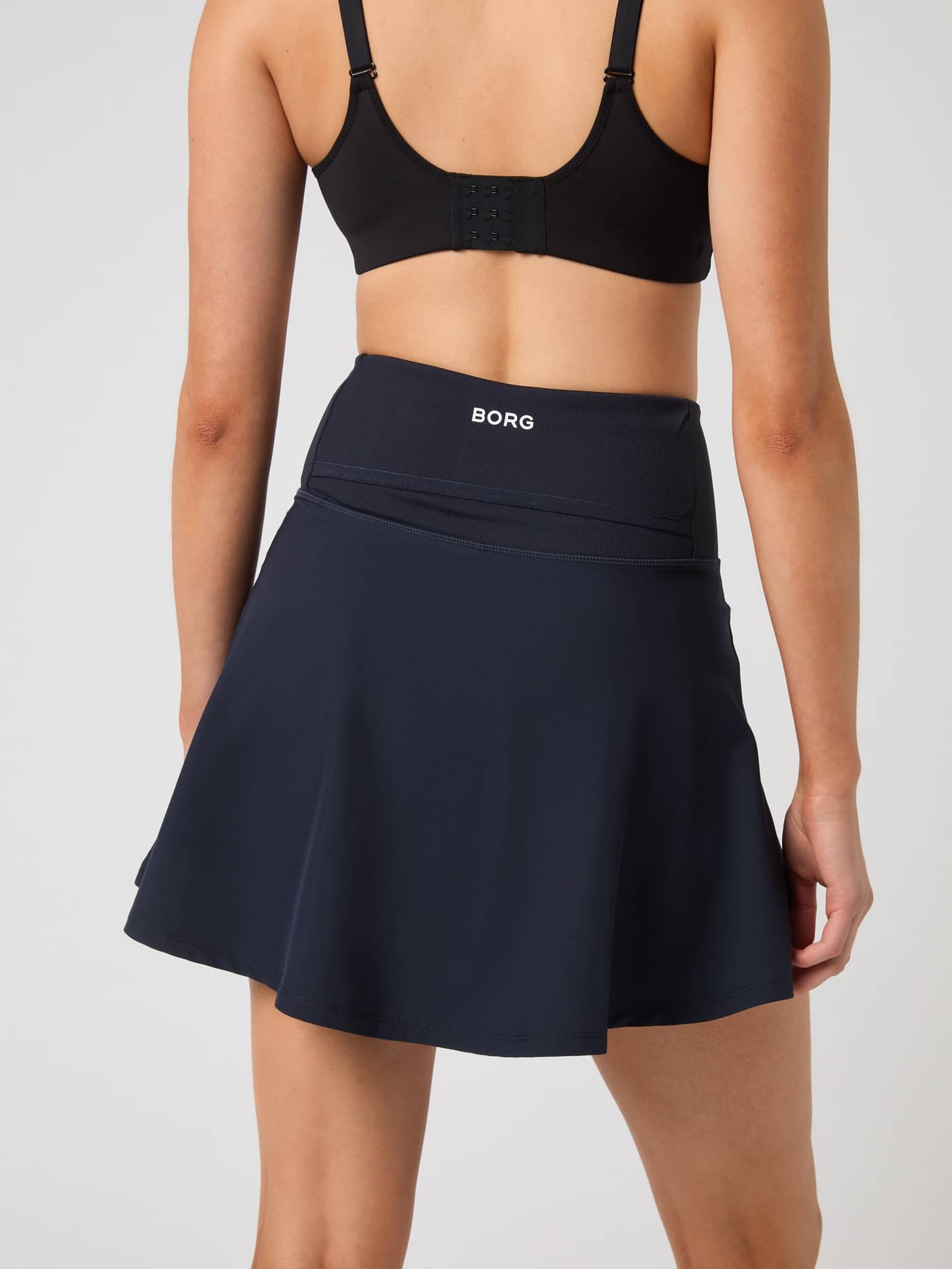 Rückansicht des Ace Skirt Pocket in Night sky (Marineblau) für Tennis mit weißem Logo am hohen Bund. - Image 3