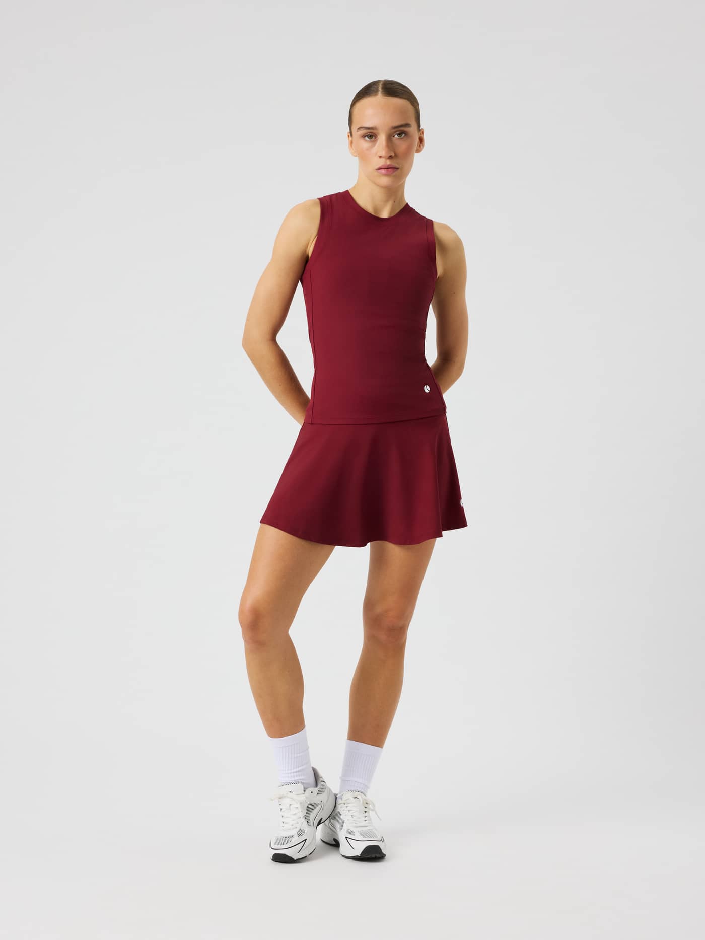 Front view of the Ace Skirt Pocket in Cabernet, featuring a high-waist design and a tennis-ball logo. - Image 1