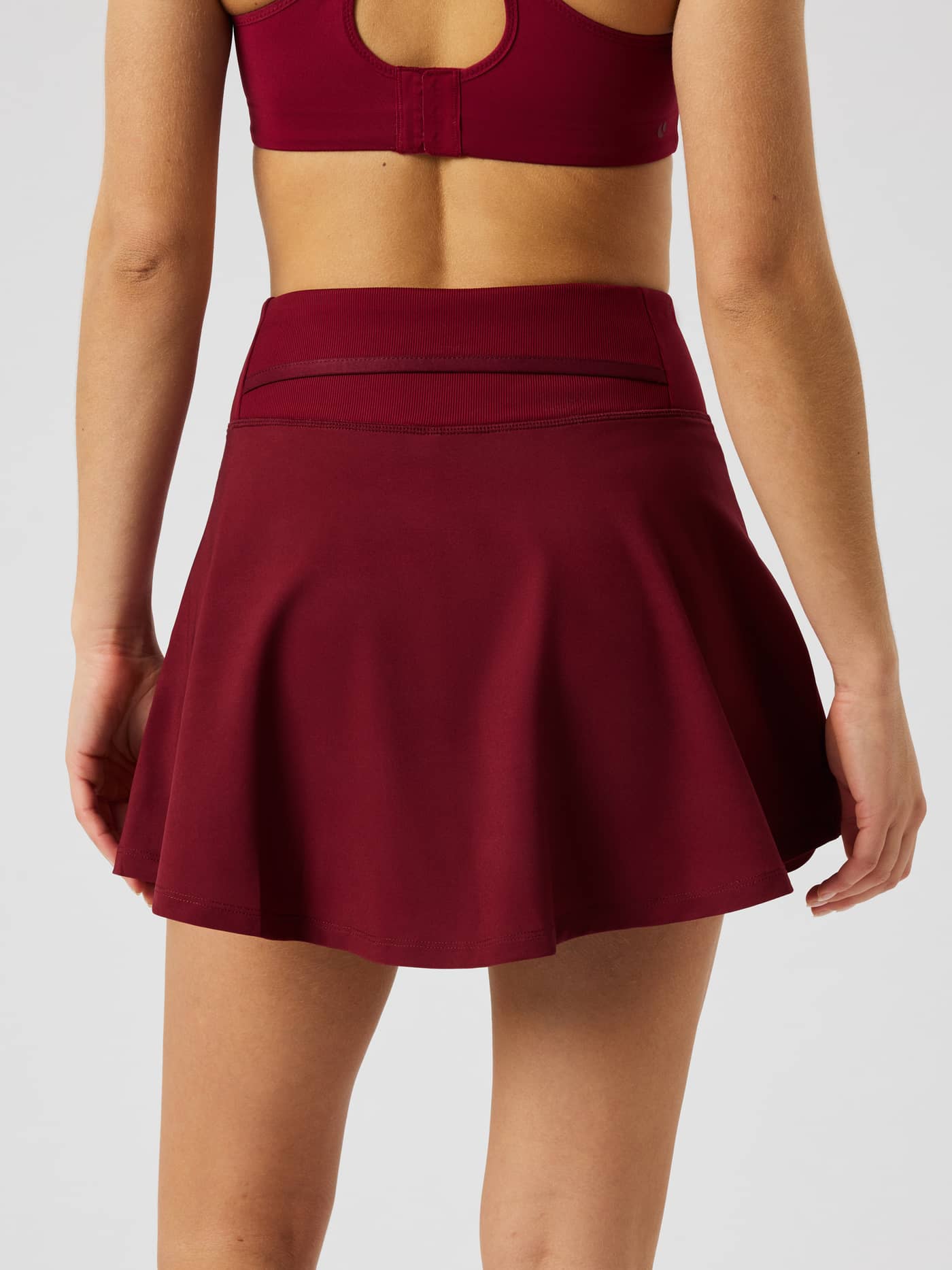 Back view of the Ace Skirt Pocket in Cabernet (Red) featuring a high waist and tennis ball pocket. - Image 3