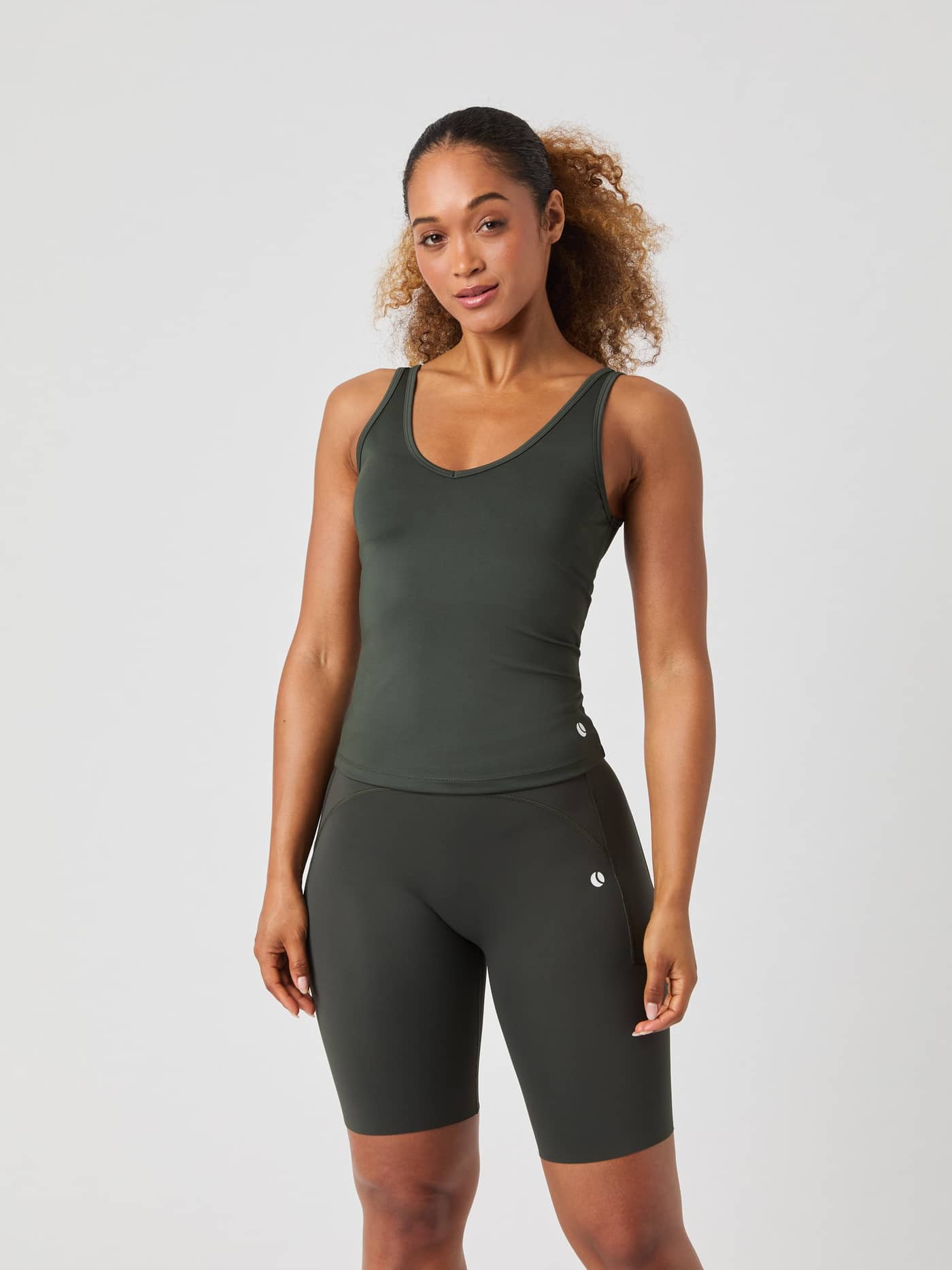 Front view of a model wearing the slim-fit Björn Borg Ace Deep V Neck Tank Top in Peat (Green) for tennis performance. - Image 1