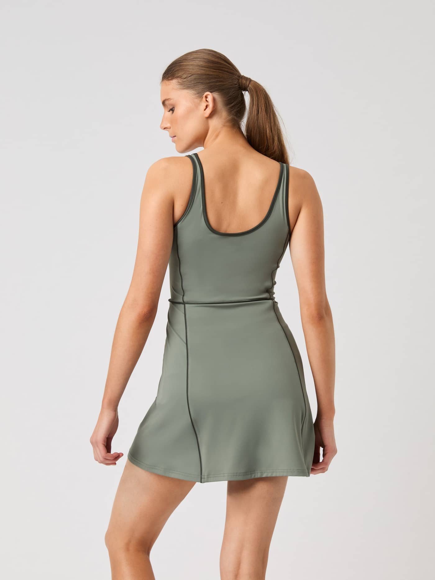 Back view of a woman wearing the Björn Borg Ace V Dress in Agave Green (Green), a regular fit tennis dress with a low back. - Image 2