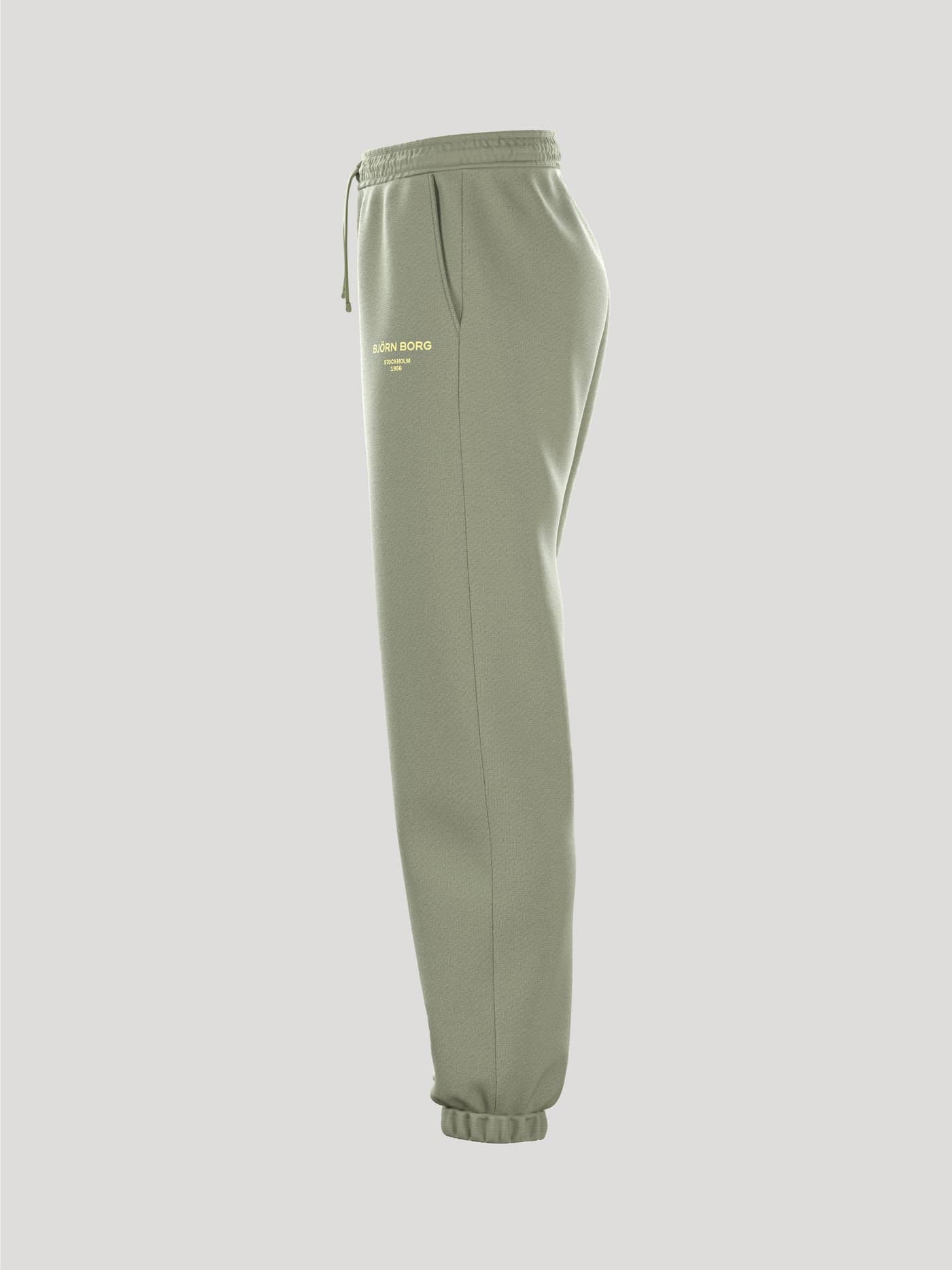 Side view of the women's Borg Essential 1 Sweatpants in green, showing the drawstring waist and cuffed ankle. - Image 4