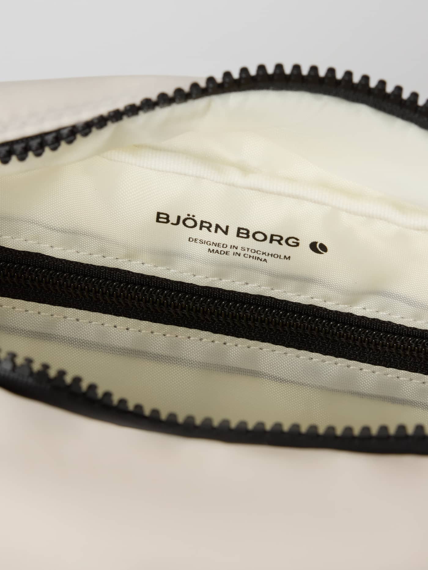 Innenansicht der Borg Classic Crossover Bag 2,5 L in Birch (Weiß) mit schwarzem Björn Borg Logo und Reißverschlussfach. - Image 5