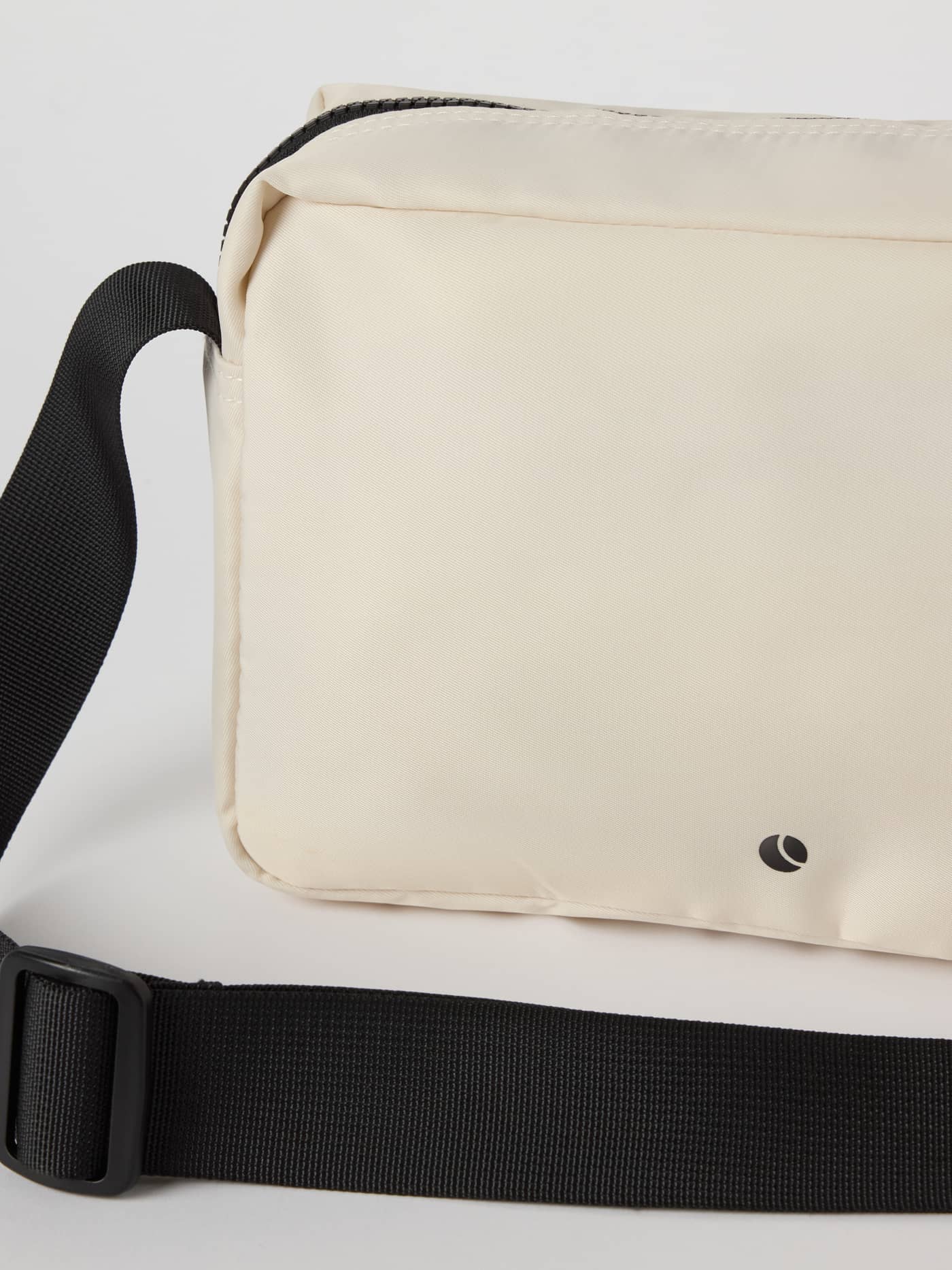 Detailaufnahme der Borg Classic Crossover Bag 2,5 L in Birch (Weiß) mit schwarzem Logo und verstellbarem Riemen. - Image 4