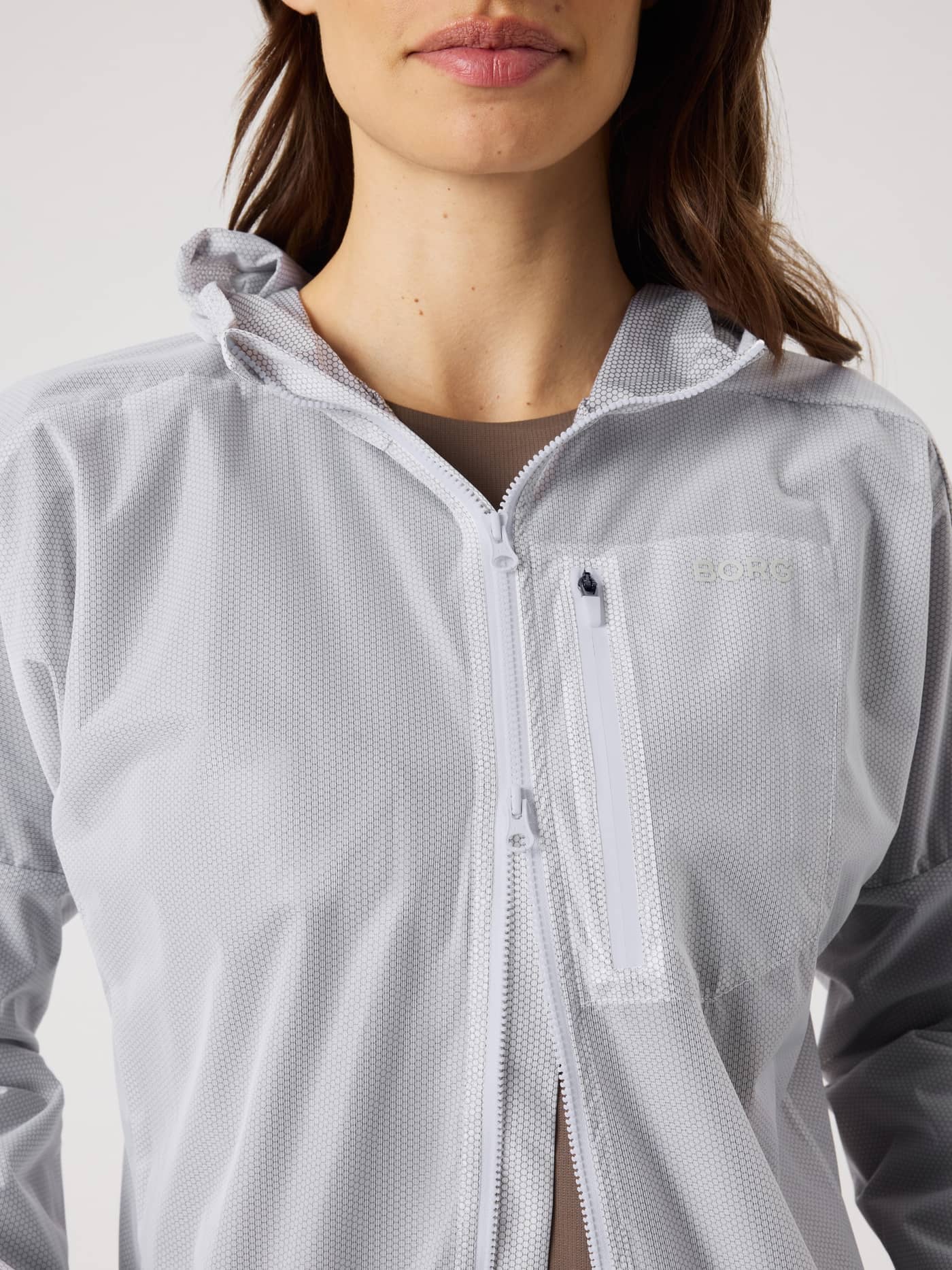 Nahaufnahme der Damen Björn Borg Running Jacket in Brilliant White (Weiß) mit Wabenmuster und weißem Logo beim Laufen. - Image 5