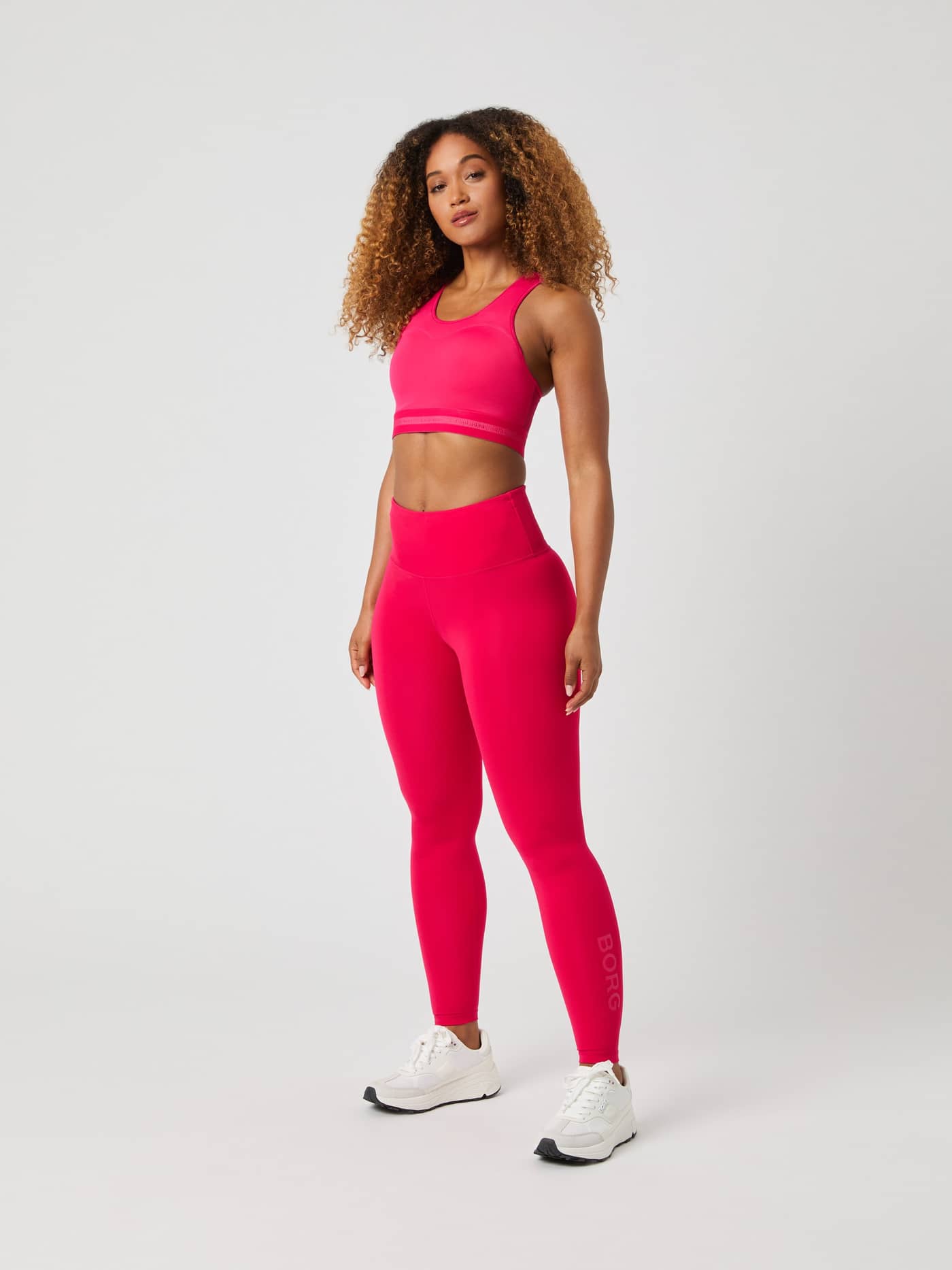 Full-body front view of a woman wearing the pink Borg High Support Bra, designed for high-intensity training and running. - Image 3