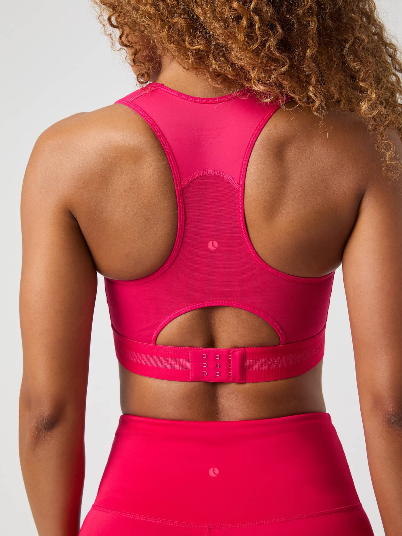Back view of a model wearing the pink Borg High Support Bra, featuring a breathable racerback and power mesh for running. - Image 5