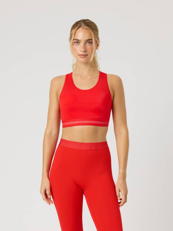 Front view of a model wearing the Borg Performance High Support Bra in Flame Scarlet (Red) with a red logo for running.