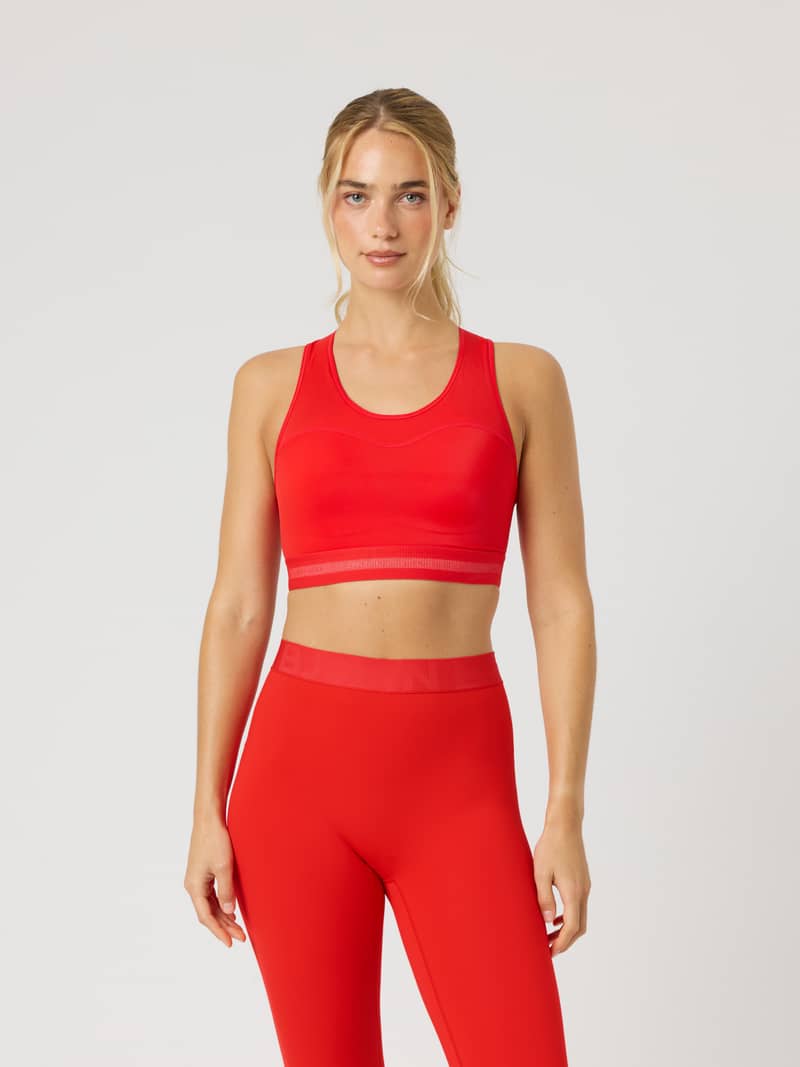 Front view of a model wearing the Borg Performance High Support Bra in Flame Scarlet (Red) with a red logo for running.