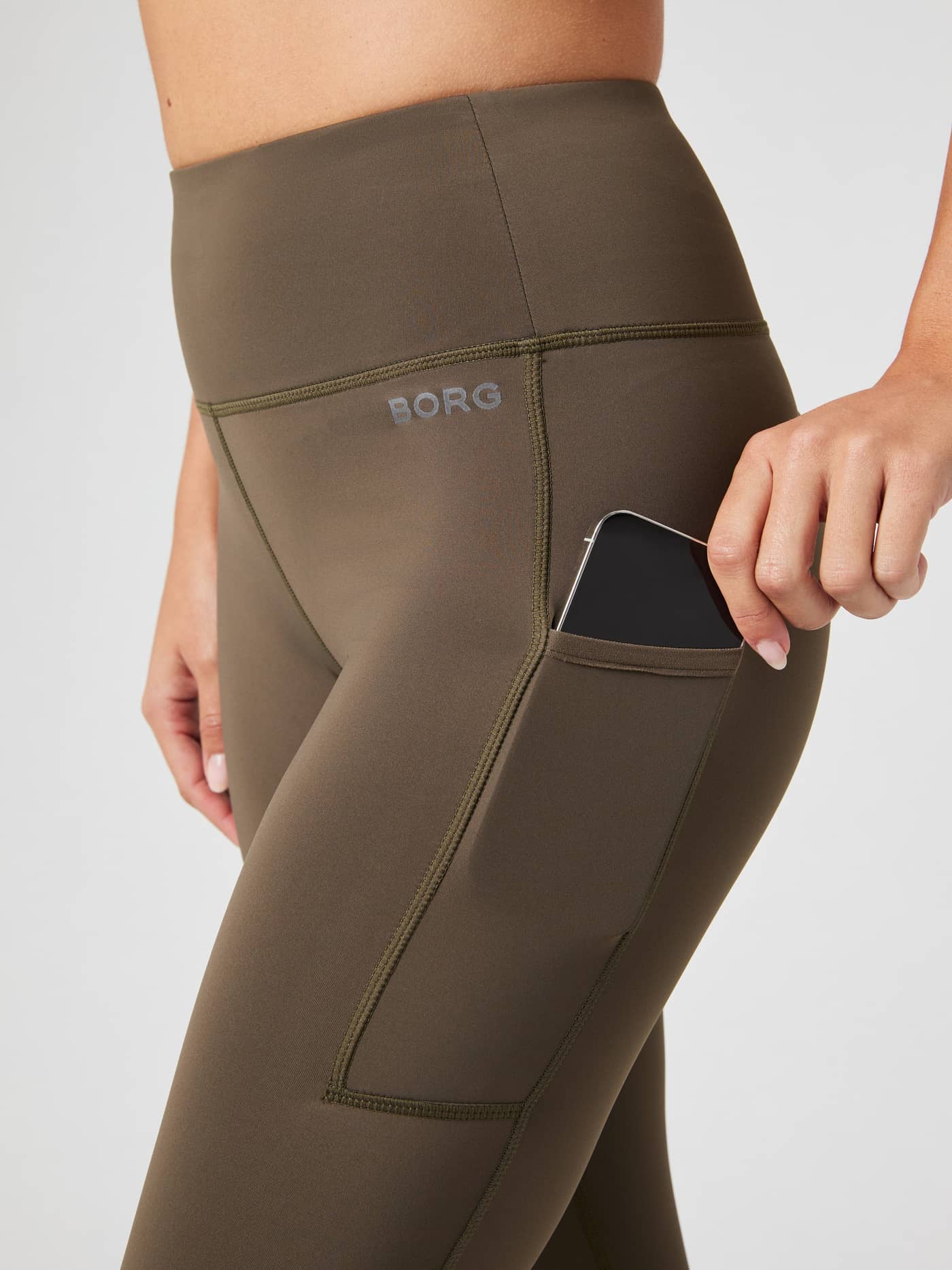 Zoom sur la poche téléphone du Borg Running Tights Crocodile (Marron) avec logo réfléchissant, idéal pour le running. - Image 4