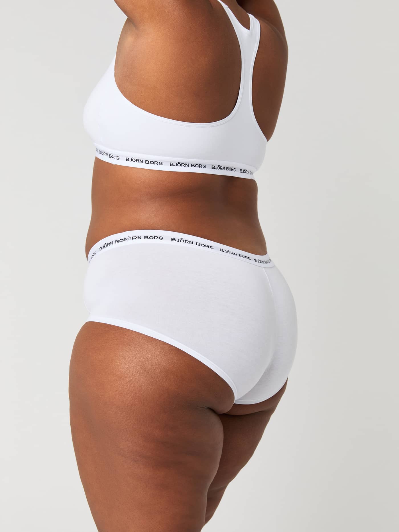 Side view of a woman wearing white Björn Borg Logo Boxer Shorts 3-pack in cotton stretch with a black and white waistband. - Image 5