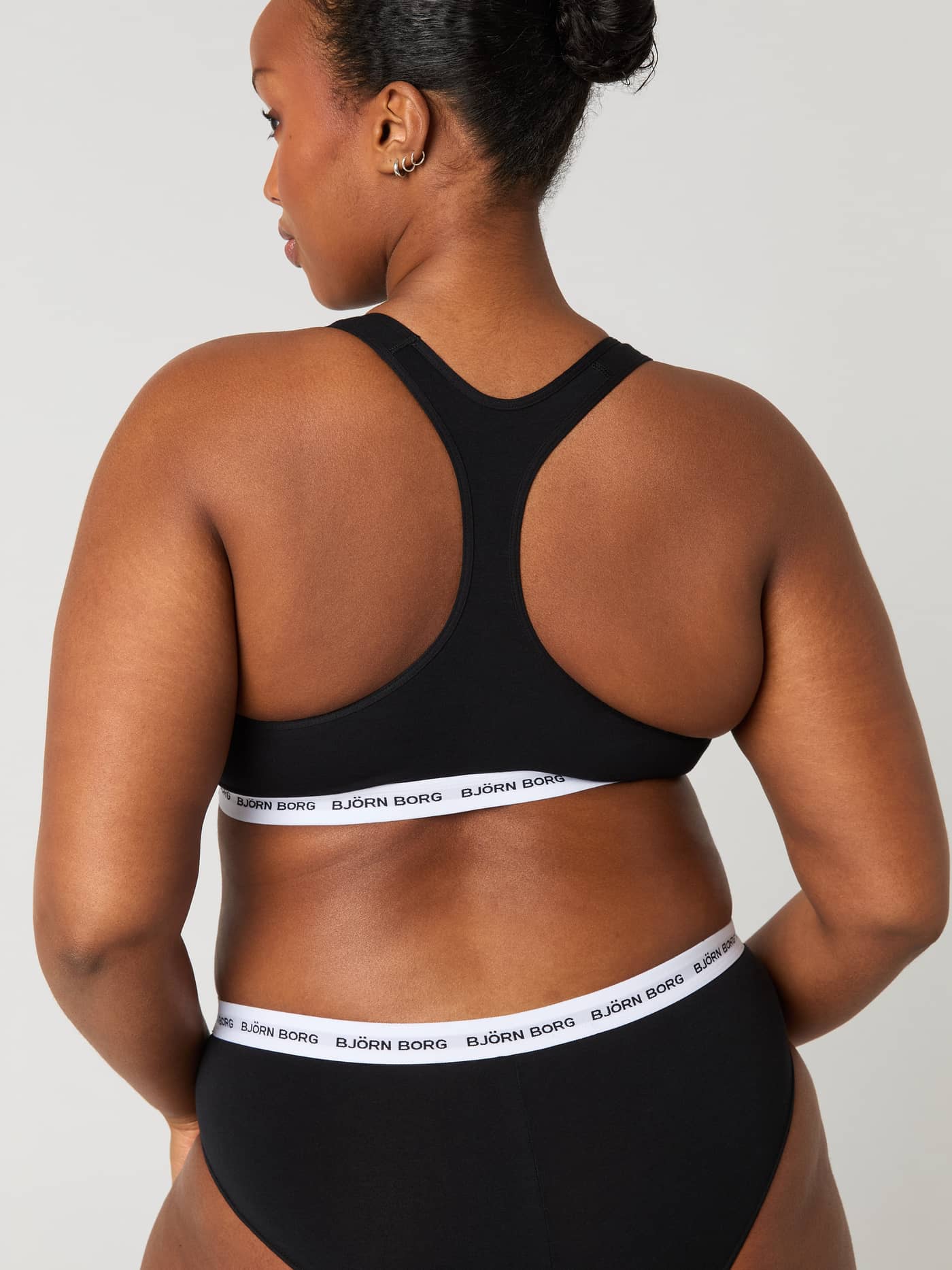Back view of a black cotton Logo Soft Top, featuring a racerback and white elastic with black logos for a great fit. - Image 2