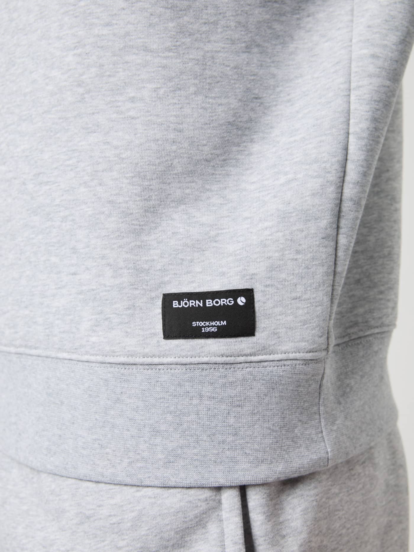 Close-up of the Björn Borg Centre Half Zip in light grey melange, showing the black logo label on the hip. - Image 4