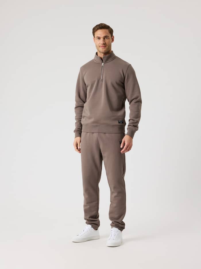 Vue en pied d'un homme portant le Centre Half Zip en Falcon (Marron) avec demi-zip et étiquette logo noire. - Image 3