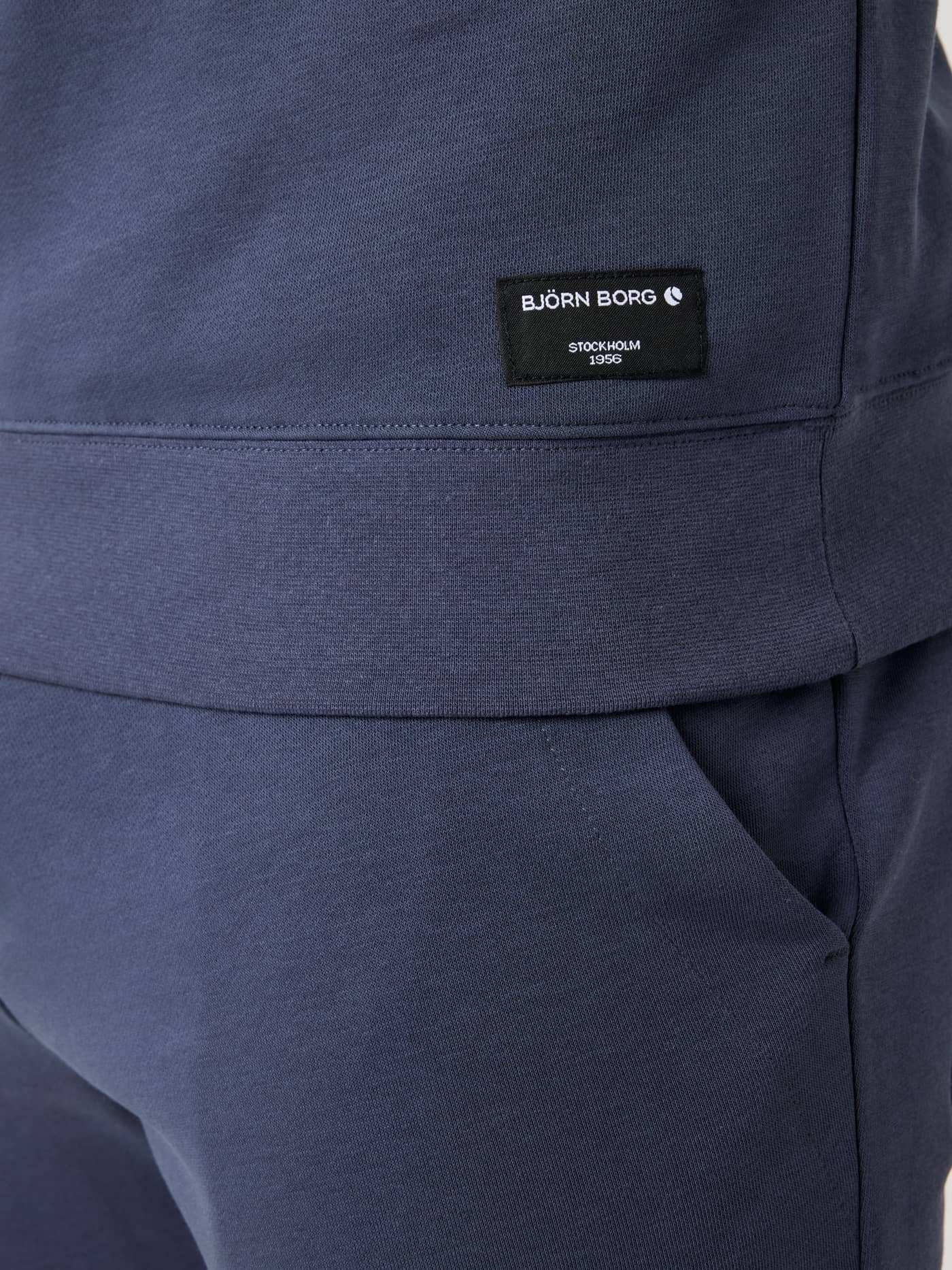 Detailed view of the Björn Borg Centre Half Zip in Odyssey Gray (Blue), showcasing the black logo label on the hip. - Image 5