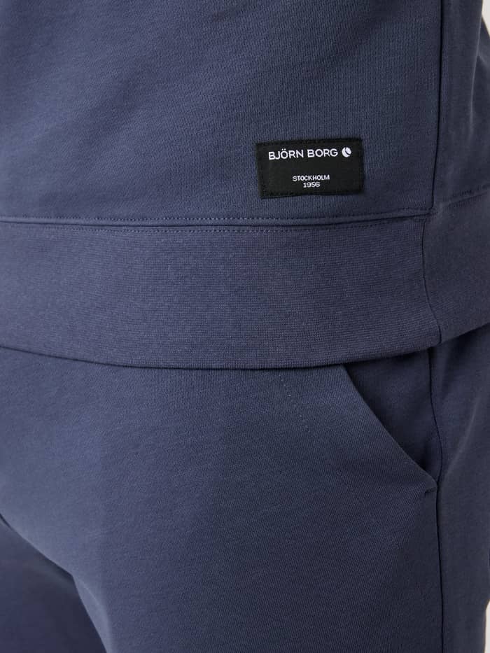 Detailed view of the Björn Borg Centre Half Zip in Odyssey Gray (Blue), showcasing the black logo label on the hip. - Image 5
