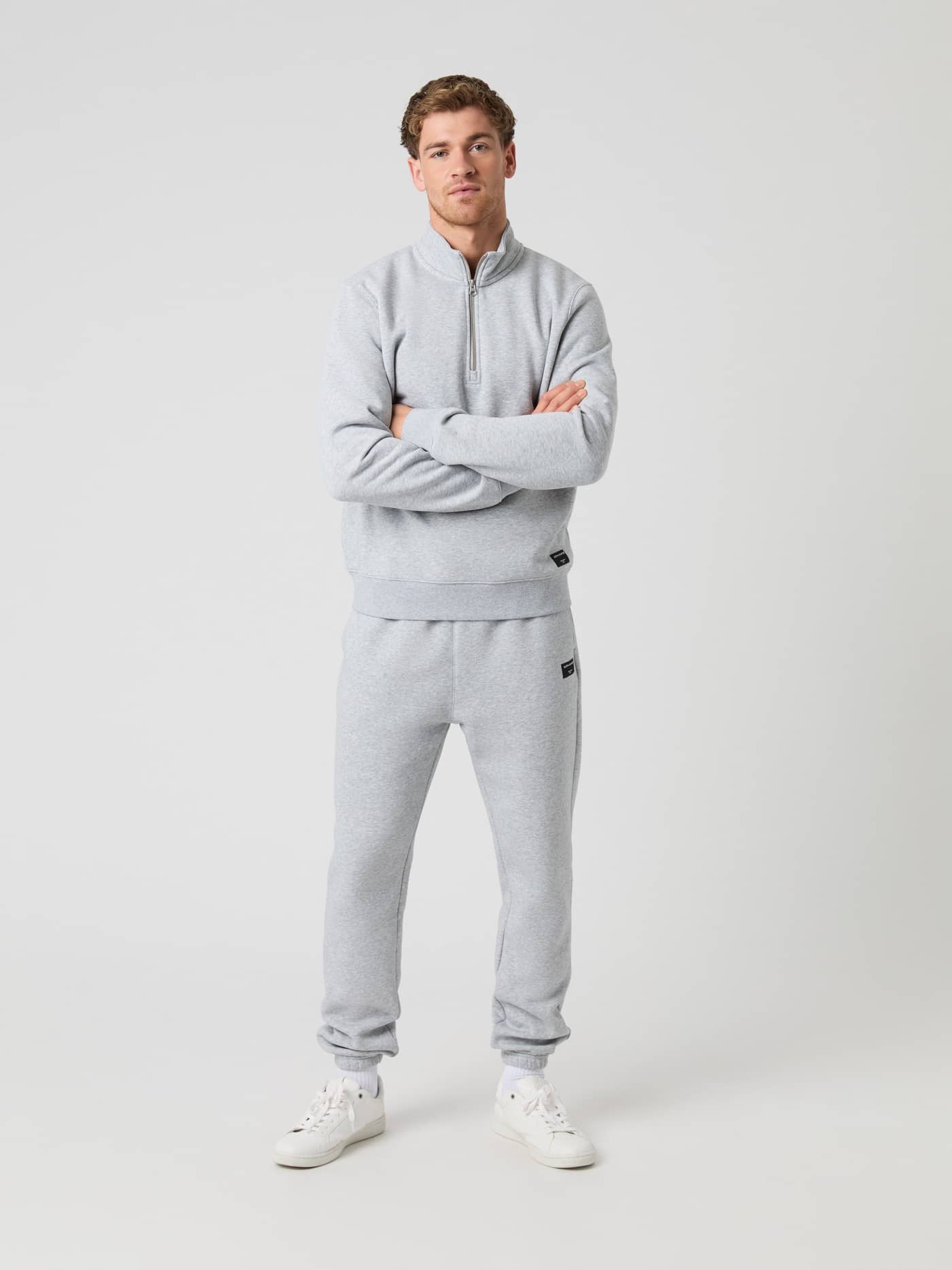 Man wearing the Björn Borg Centre Half Zip sweater in light grey melange with matching track pants, arms crossed. - Image 3