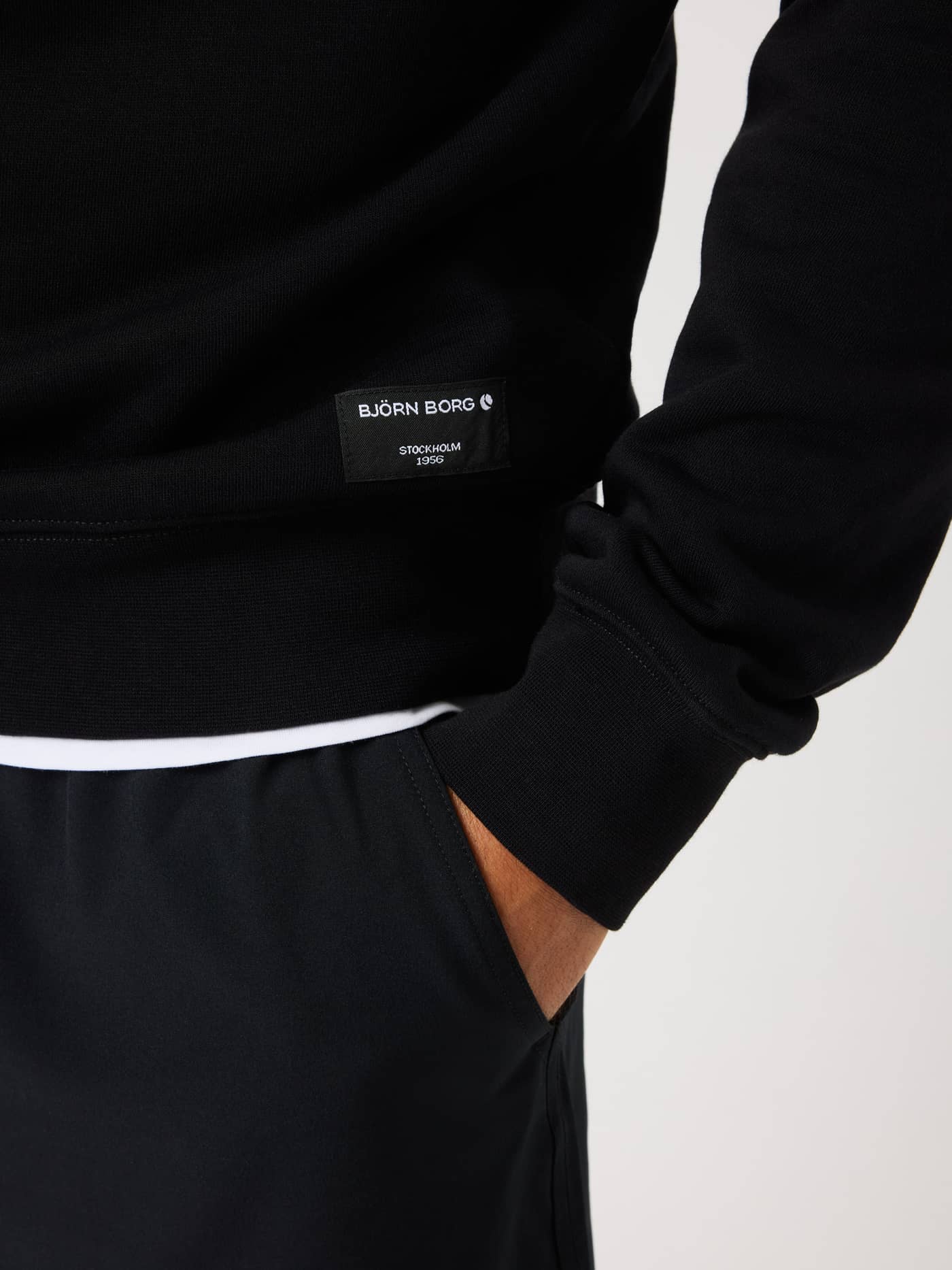 Close-up of the Centre Half Zip in Black Beauty (Black) featuring a woven hip label with a white Björn Borg logo. - Image 4