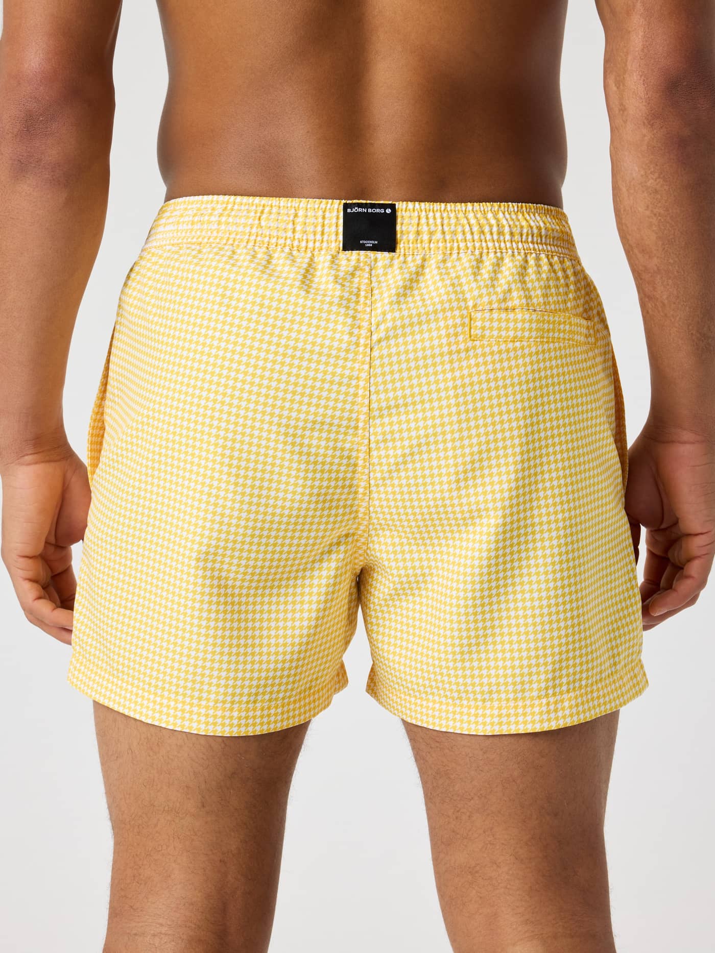 Vista trasera de Borg Print Swim Shorts en Houndstooth 2 (Amarillo) con estampado de pata de gallo y parche de logo negro. - Image 2