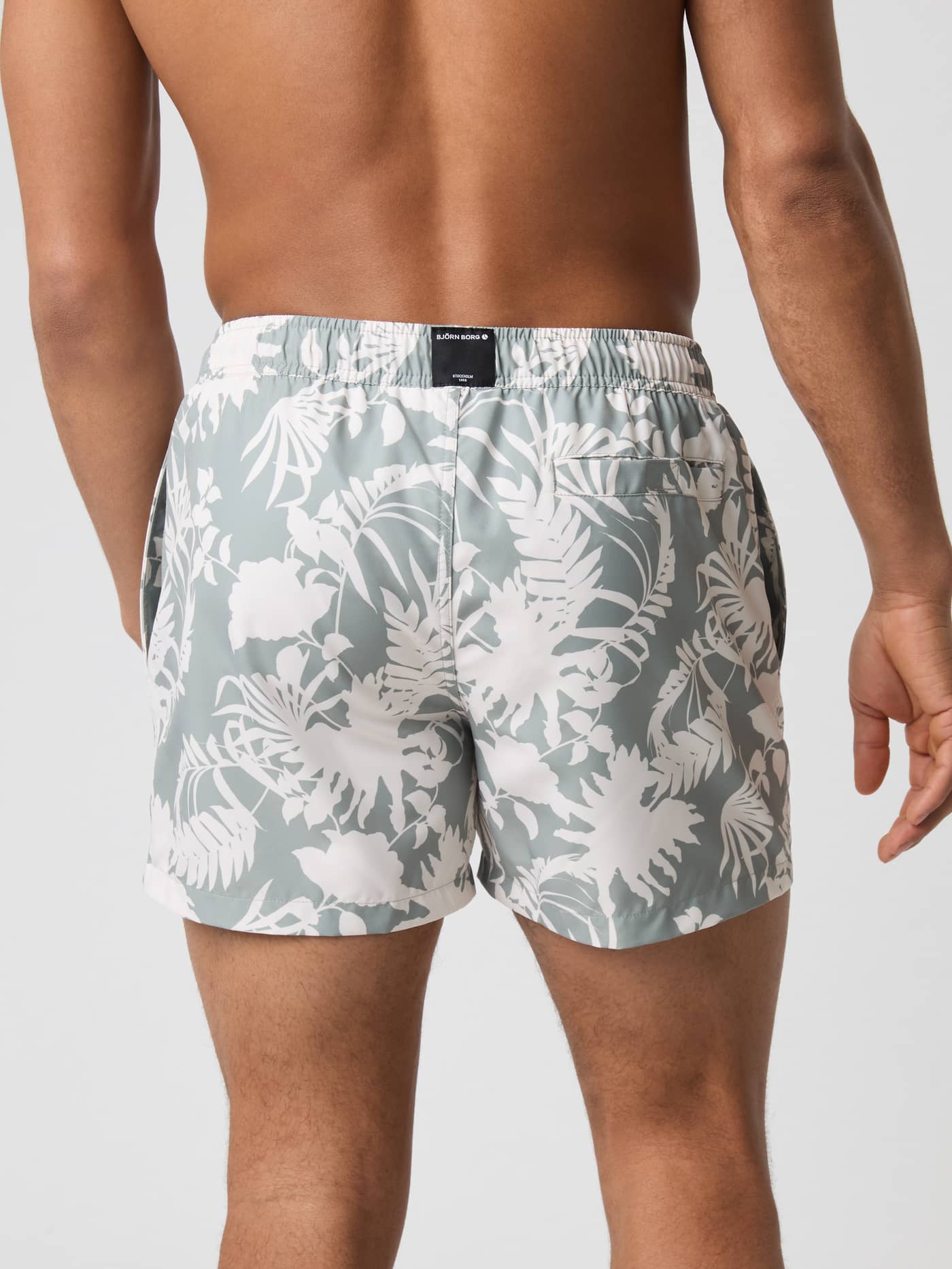 Borg Print Swim Shorts i Dark Jungle 5 (Grön) sedda bakifrån med botaniskt mönster och en svart logotyp. - Image 3