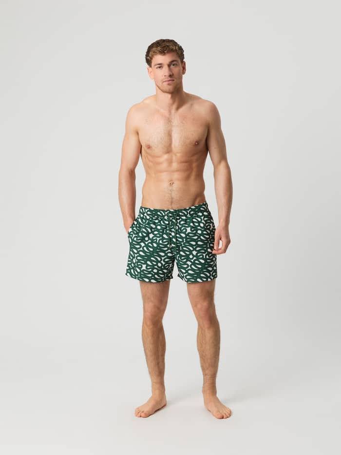 Full-body front view of a man in quick-drying Björn Borg Print Swim Shorts in Serpent Big 1 (Green) with a white print.