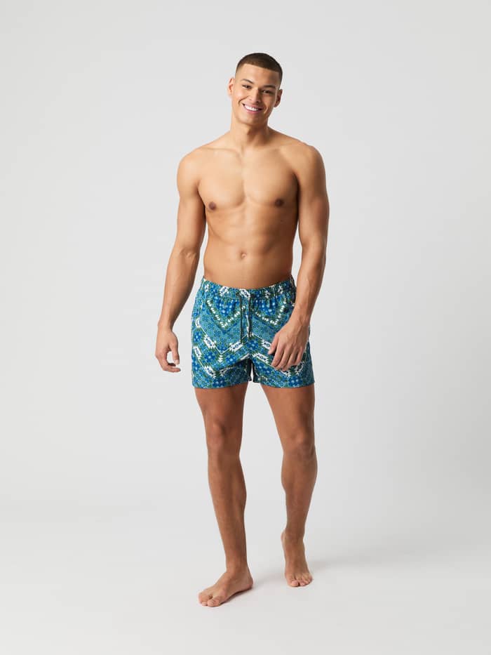 Mann sett forfra i hurtigtørkende Borg Print Swim Shorts i East Ikat (Blå) for strandstil og funksjon.