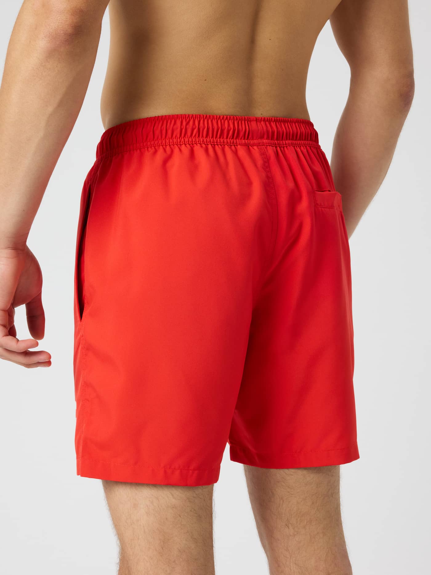 Back view of a man wearing solid Flame Scarlet (Red) Borg Swim Shorts featuring a functional back pocket and elastic waist. - Image 2