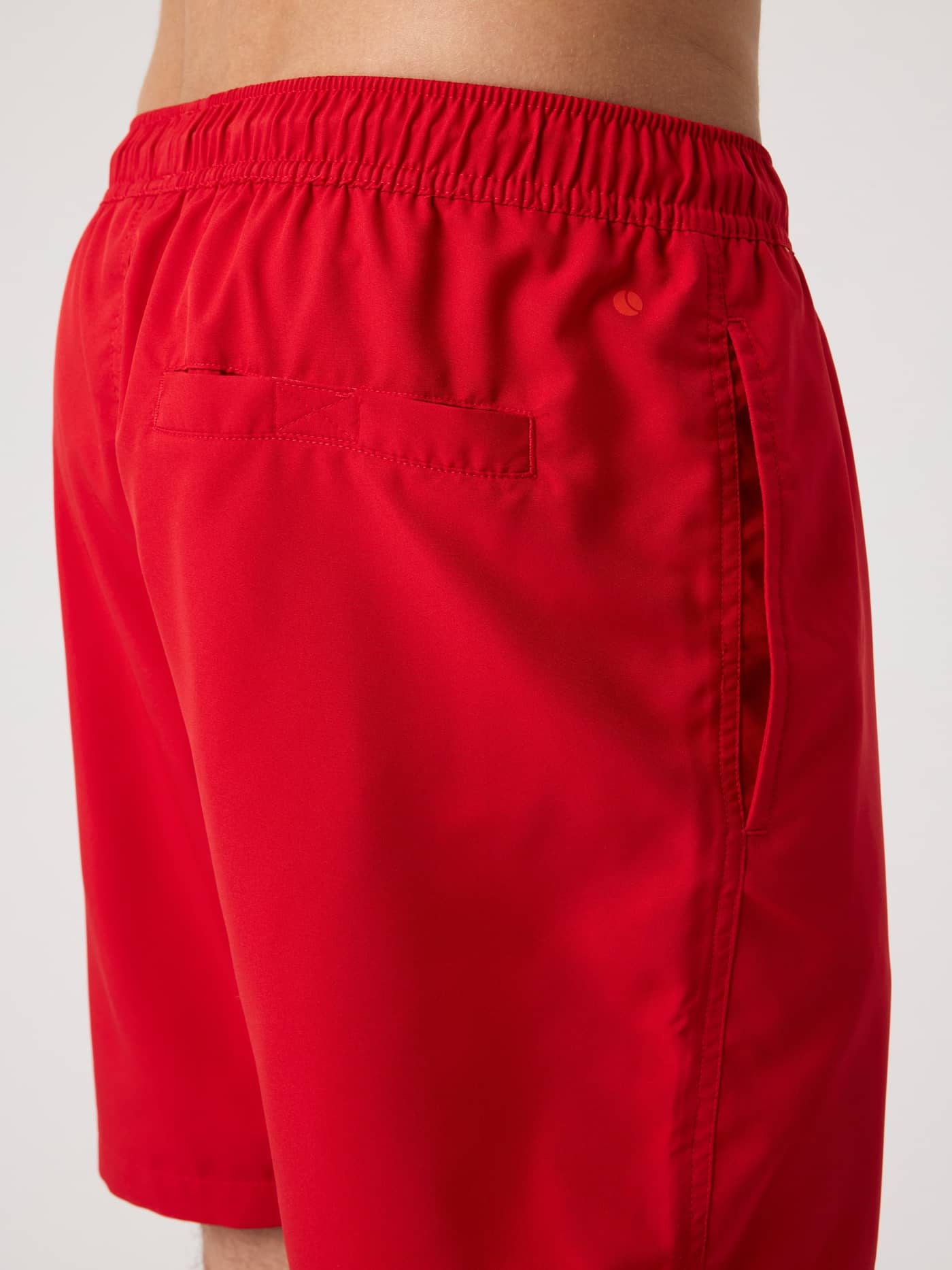 Detailed side view of the Pompeian Red (Red) Borg Swim Shorts for men, featuring recycled fabric and a tennis ball print. - Image 4