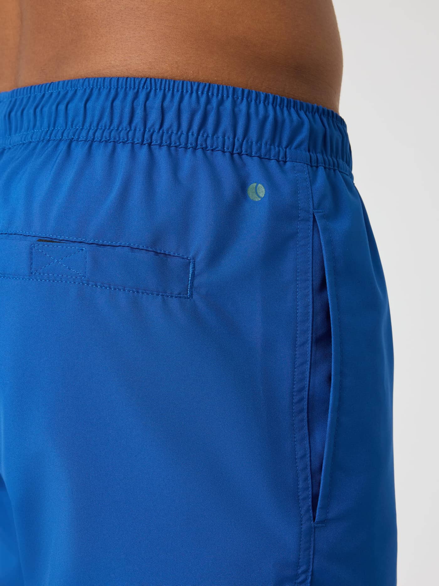 Zijaanzicht van de Borg Swim Shorts in Monaco Blue (Blauw) met een functionele zijzak en een groen tennisballogo. - Image 4
