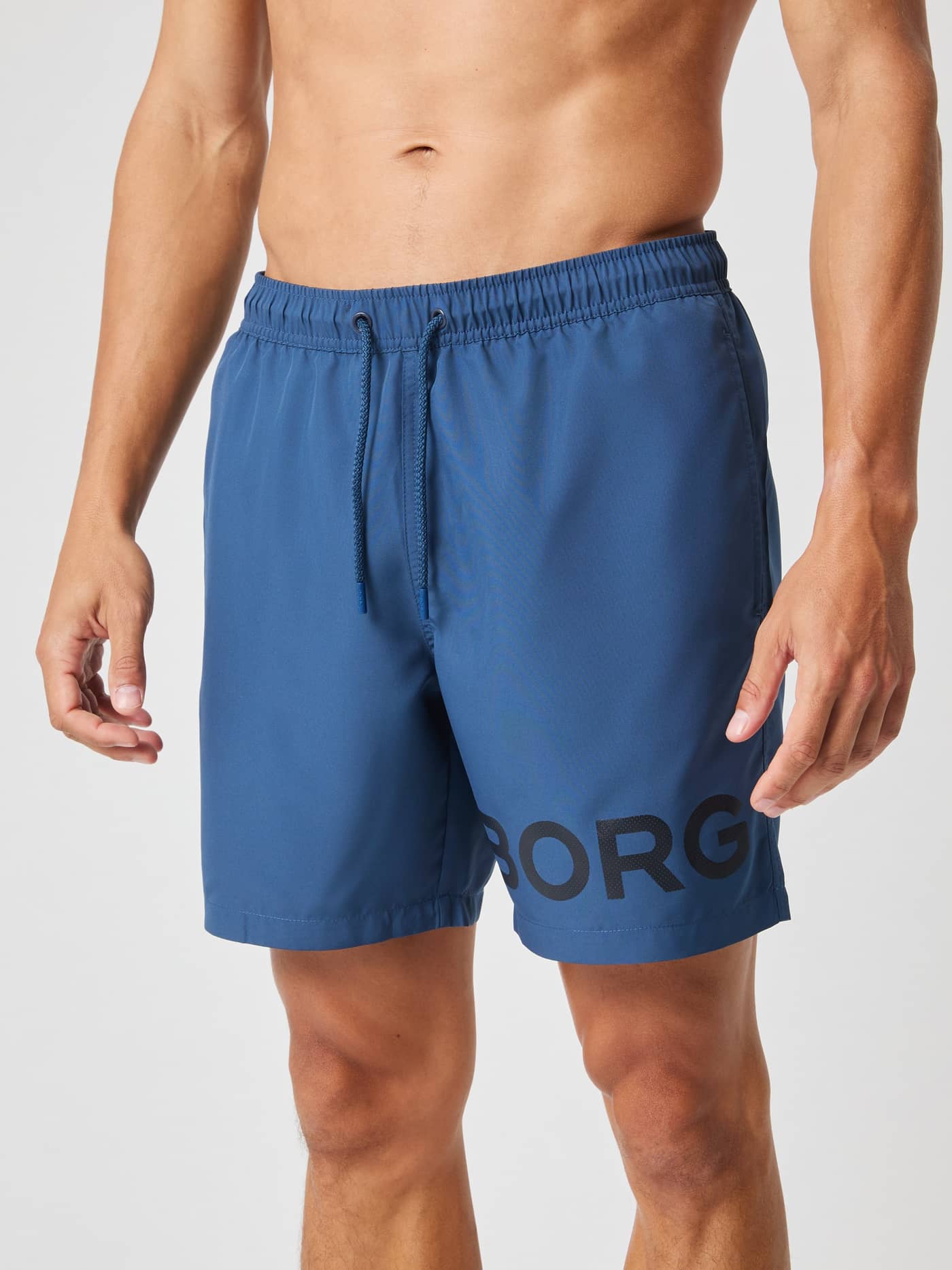 Front view of a man wearing regular-fit, quick-drying Borg Swim Shorts in Sargasso Sea (blue) with a black logo. - Image 2