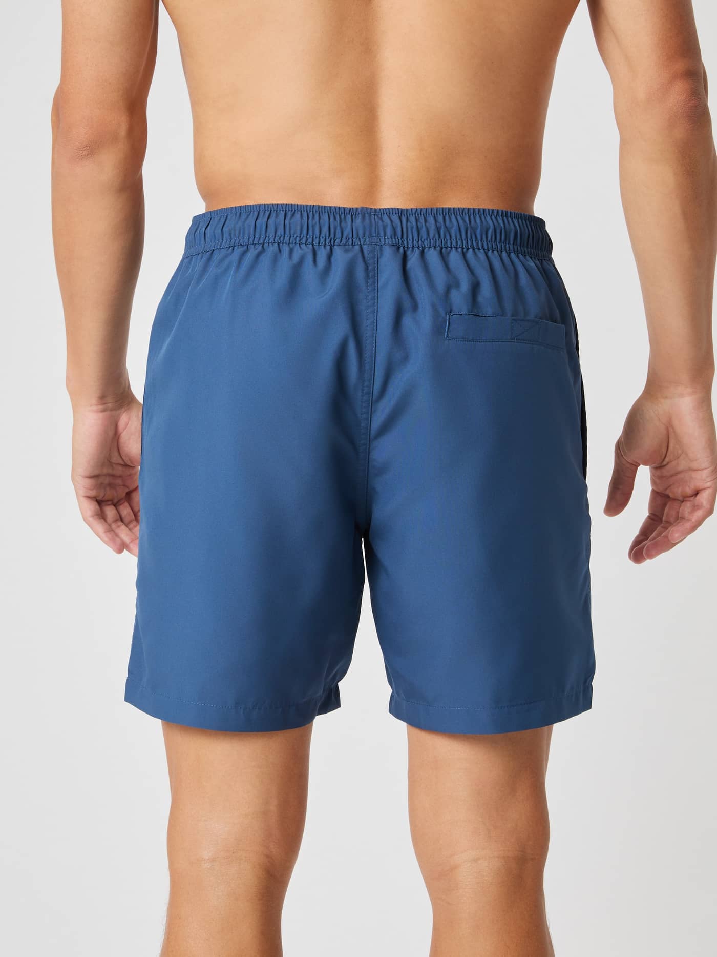 Back view of a model wearing the Borg Swim Shorts in Sargasso Sea (Blue), featuring a secure Velcro back pocket. - Image 3