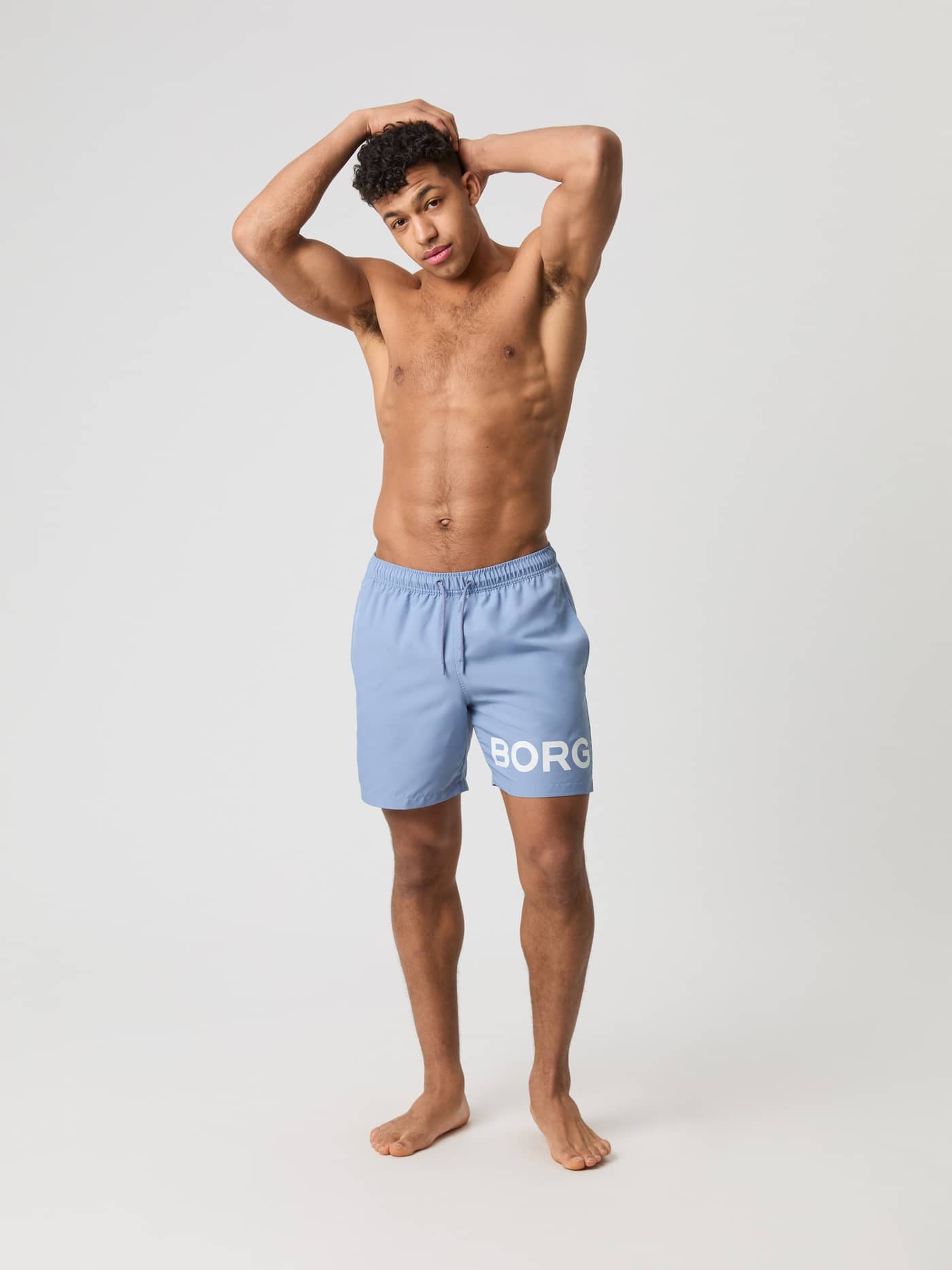 Snabbtorkande Borg Swim Shorts i Stonewash (Blå) med vit logotyp och dragsko sedda framifrån i helfigur på en man. - Image 3