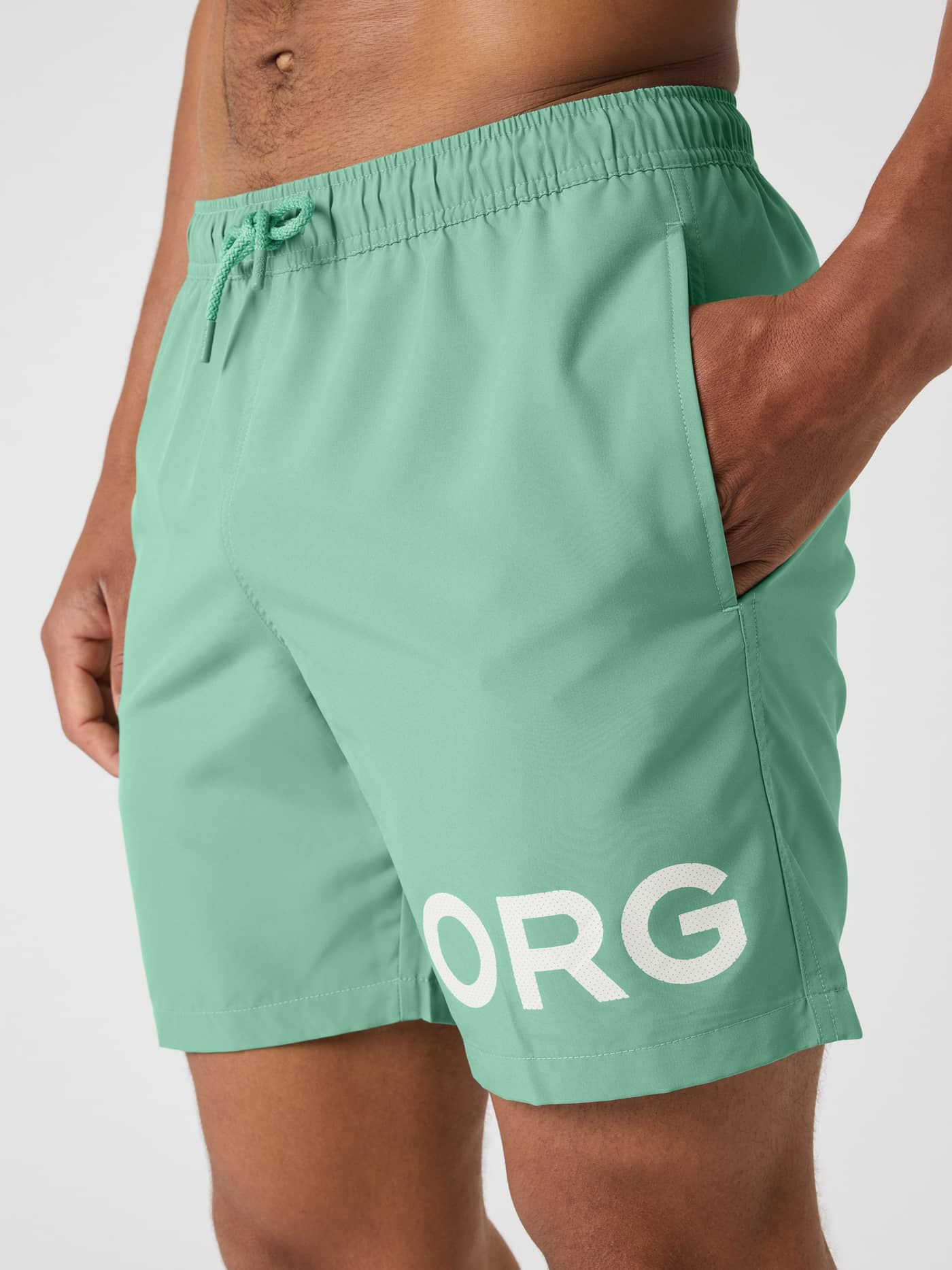 Close-up side view of a man wearing quick-drying Borg Swim Shorts in Malachite Green (Green) with a white logo and pocket. - Image 5