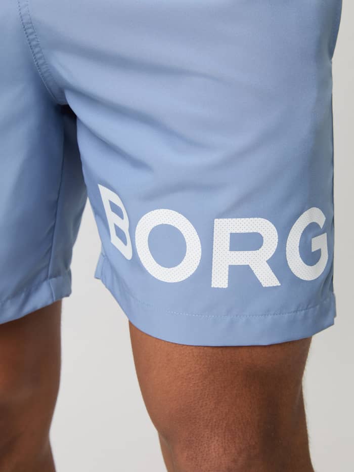 Gedetailleerde close-up van het witte logo op de sneldrogende Borg Swim Shorts voor heren in Stonewash (Blauw). - Image 4