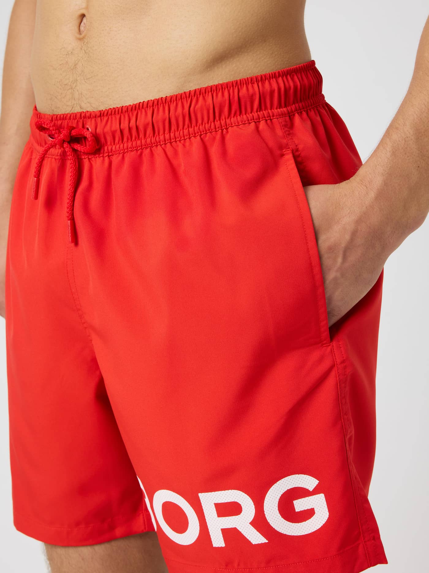 Close-up of Borg Swim Shorts in Flame Scarlet (Red) featuring a large white logo and adjustable drawstring waist. - Image 4