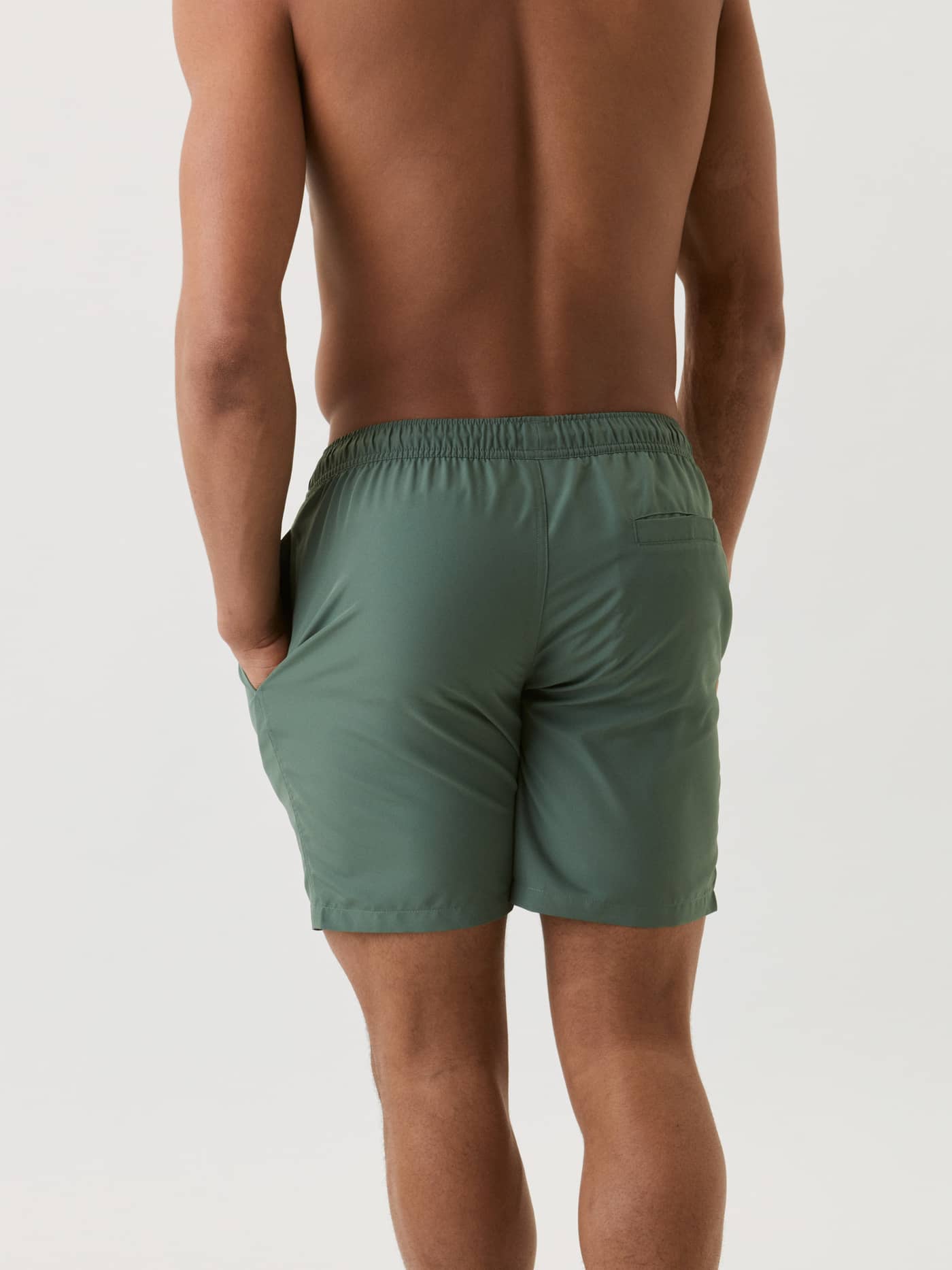 Back view of a man wearing the quick-drying, regular fit Borg Swim Shorts in Duck Green (Green) with a secure back pocket. - Image 3