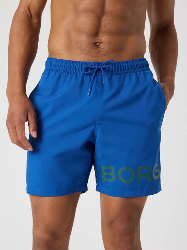 Vue de face du Borg Swim Shorts en Monaco Blue (Bleu) à séchage rapide doté d'un logo vert.