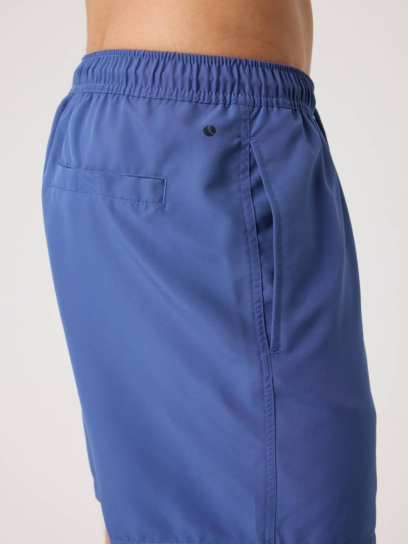 Vista lateral de los Borg Swim Shorts en Coastal Fjord (Azul) con bolsillos funcionales y logo de pelota de tenis negro. - Image 4