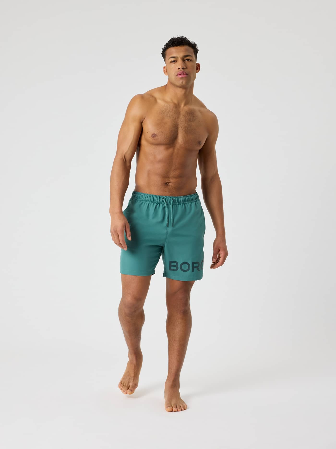 Vue de face du Borg Swim Shorts en Blue Spruce (Vert) avec un logo noir, alliant style et fonctionnalité. - Image 3