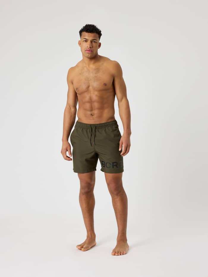 Borg Swim Shorts in Forest Night (Groen) met een groot logo op het been, getoond in vooraanzicht bij een man. - Image 3