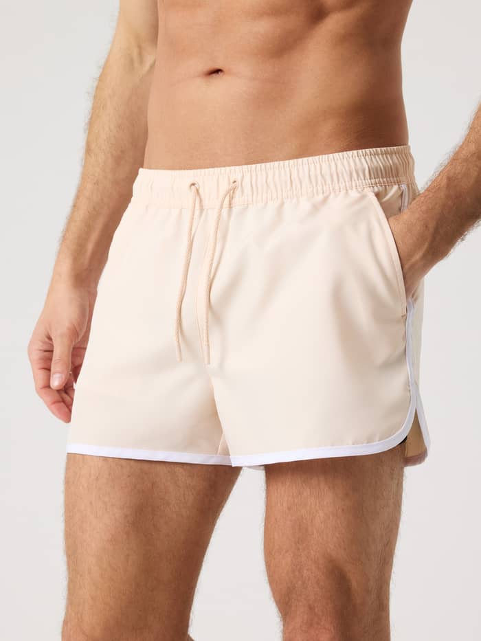 Mann i Borg Retro Swim Shorts i Creme De Peche (Rosa) med smal passform og hvite kontrastsømmer sett forfra.