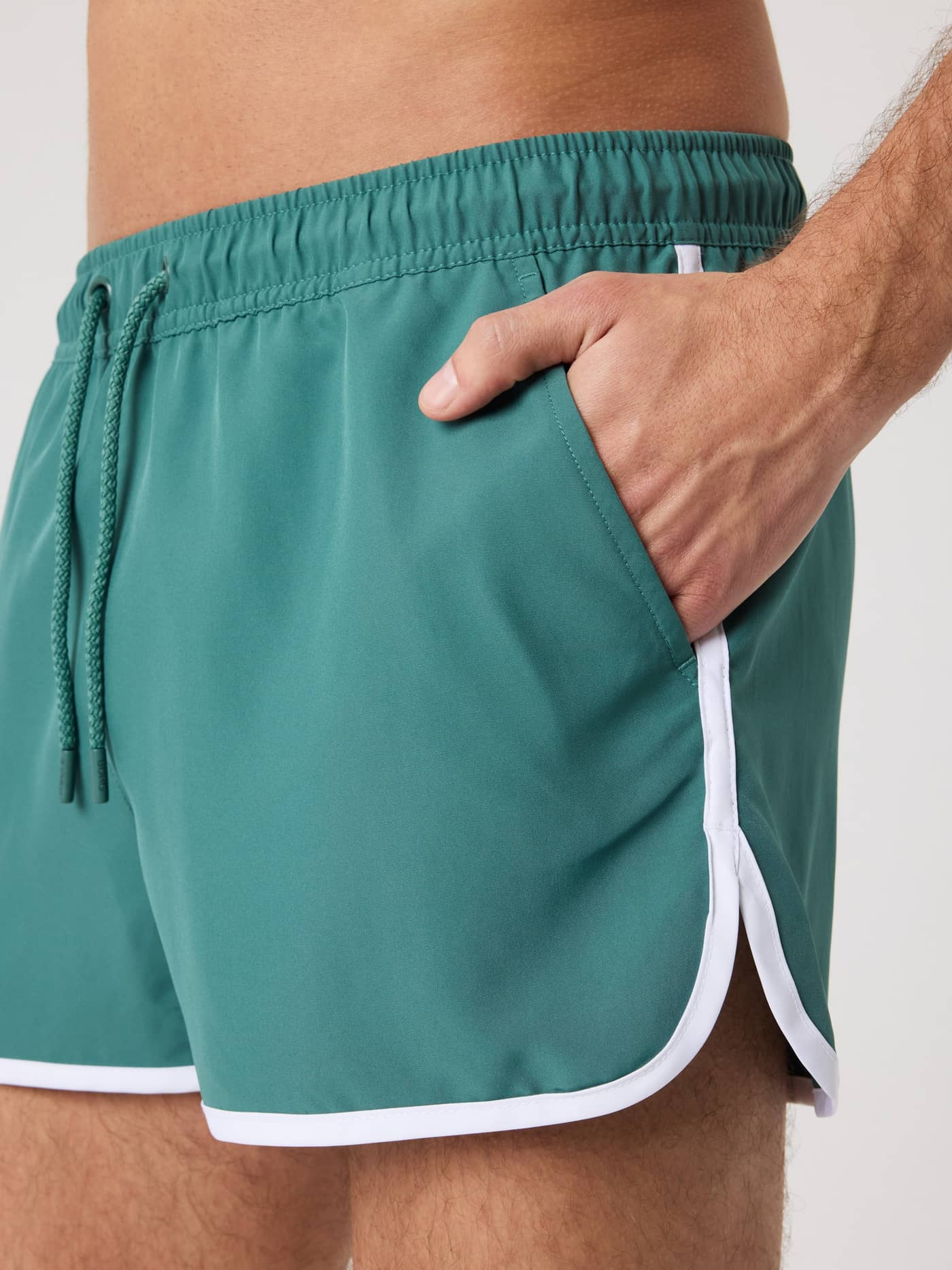 Nahaufnahme der Seitentasche der Borg Retro Swim Shorts in Blue Spruce (Grün) mit weißen Paspeln. - Image 5
