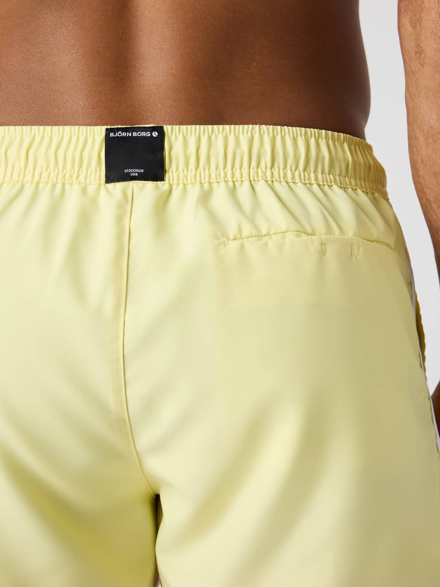 Back view of the Björn Borg Retro Swim Shorts in Lemonade (Yellow) featuring a black logo label and functional pocket. - Image 4