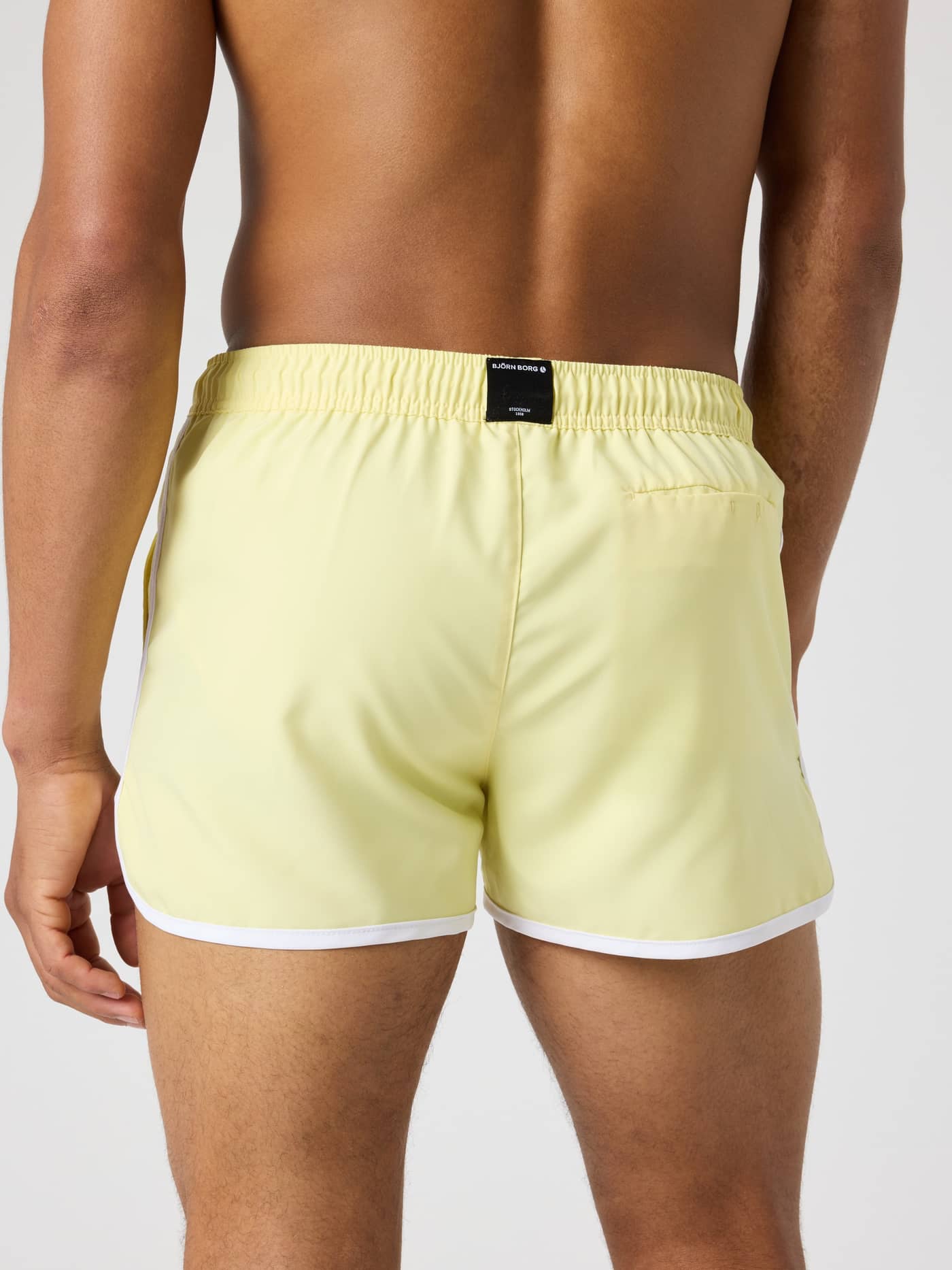 Back view of a model wearing the Björn Borg Retro Swim Shorts in Lemonade (Yellow) with white piping. - Image 2