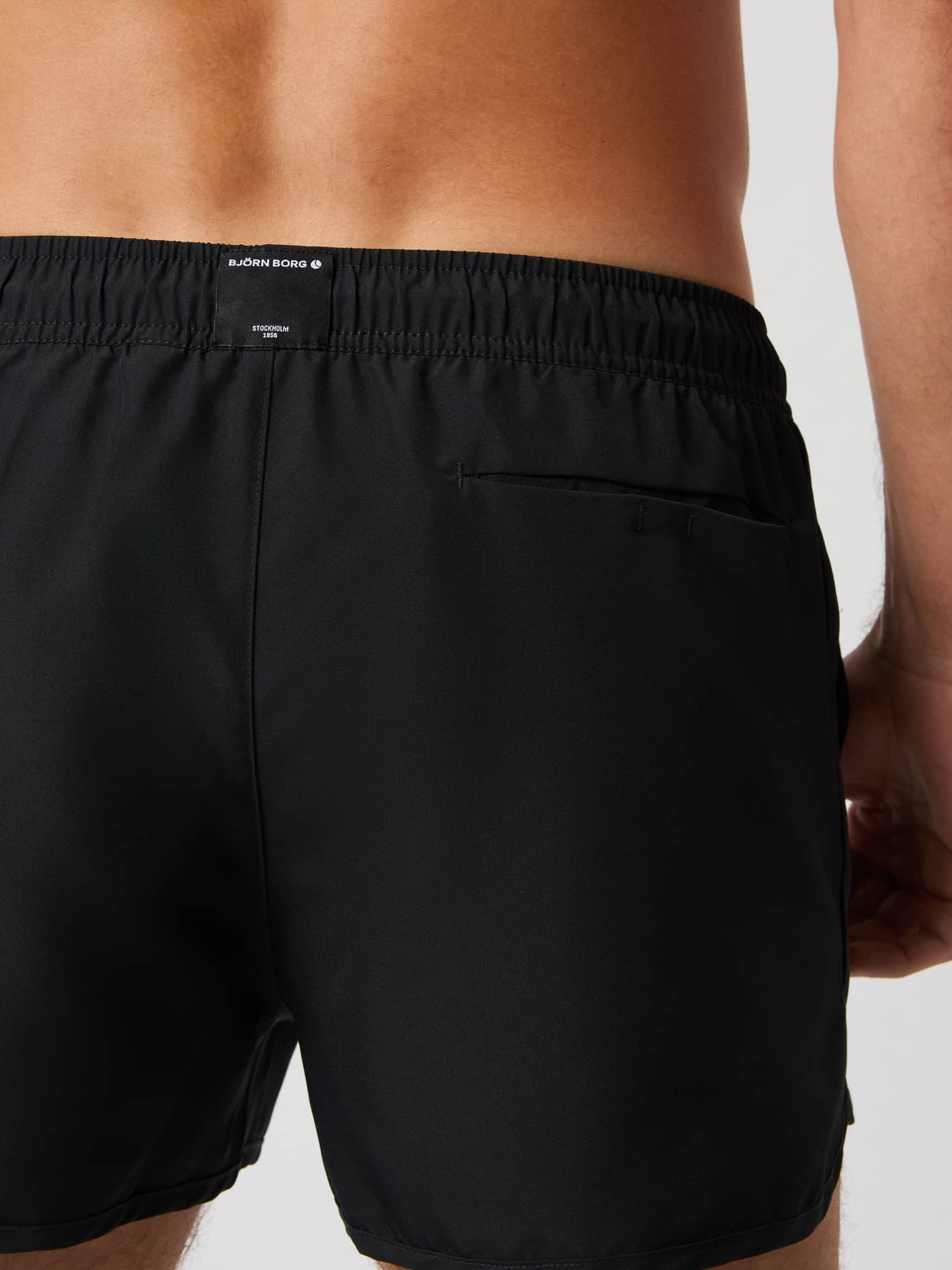 Back view of the Borg Retro Swim Shorts in Black Beauty (Black) with a white logo label and functional Velcro pocket. - Image 4