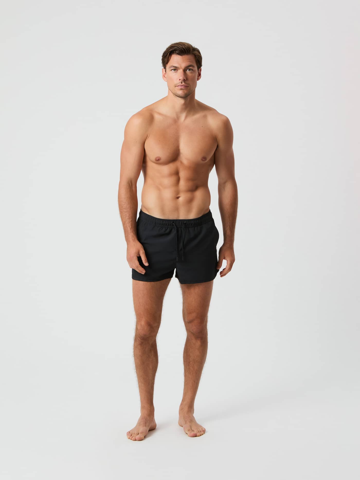 Full-body front view of a man wearing the slim-fit, quick-drying Björn Borg Retro Swim Shorts in Black Beauty (Black). - Image 2