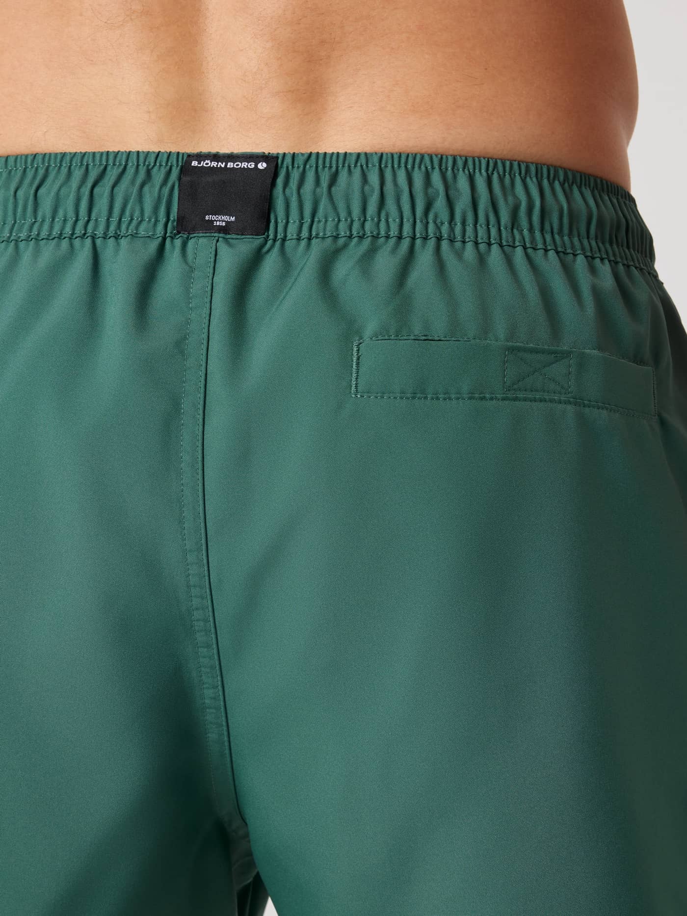 Back view of Mallard Green (Green) Borg Solid Swim Shorts in recycled polyester with a Velcro pocket and black logo label. - Image 5