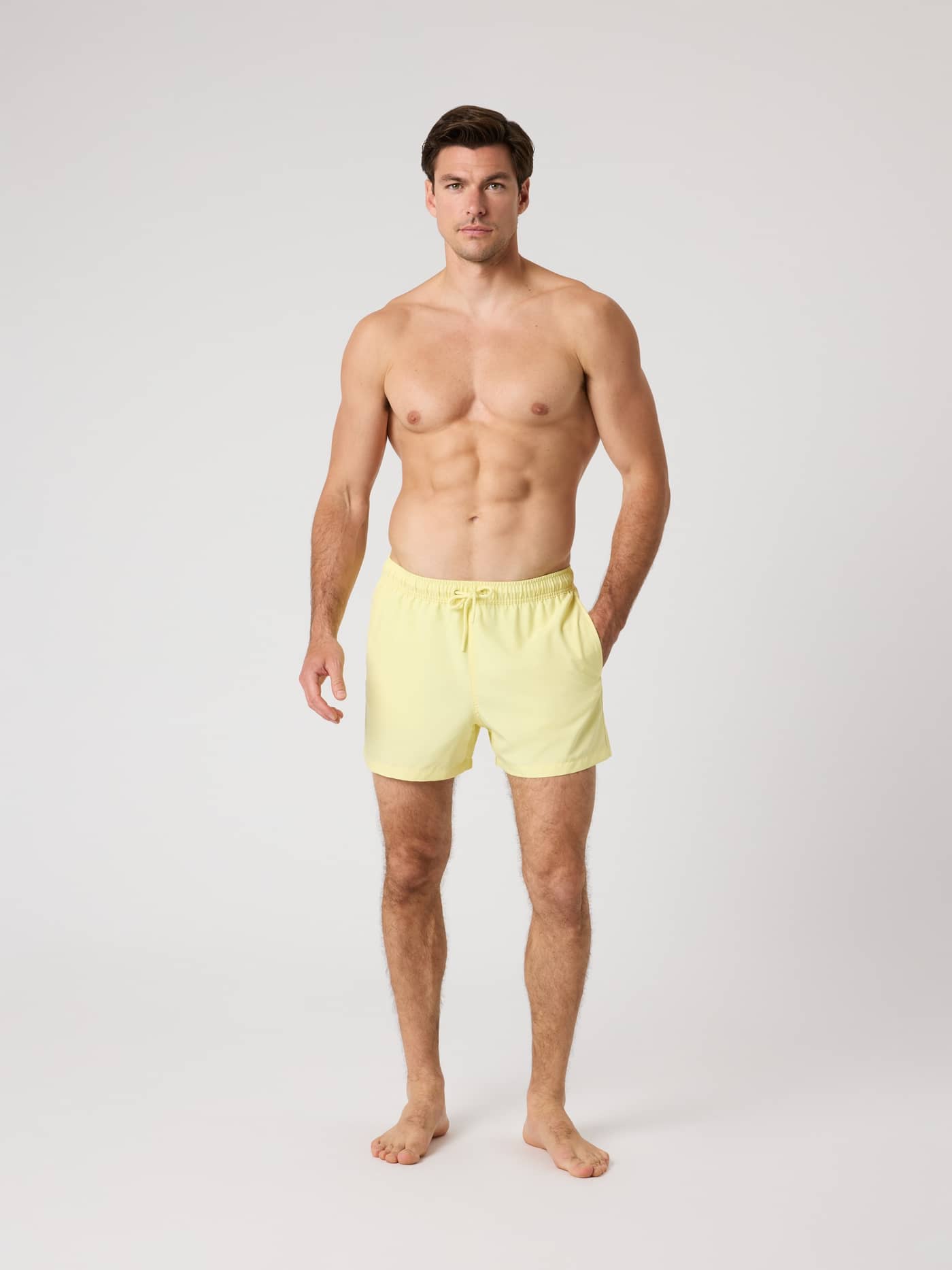 Full-body front view of a man wearing the stylish and functional Björn Borg Solid Swim Shorts in Lemonade (Yellow). - Image 3
