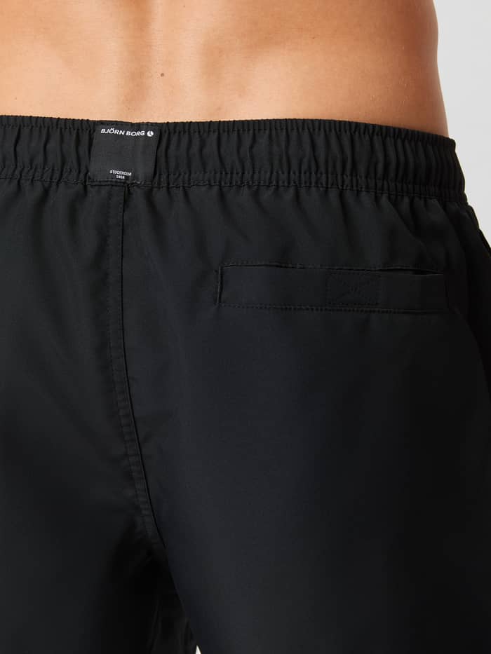 Achteraanzicht van de Borg Solid Swim Shorts in Black Beauty (Zwart) met een functionele klittenbandzak en logolabel. - Image 4